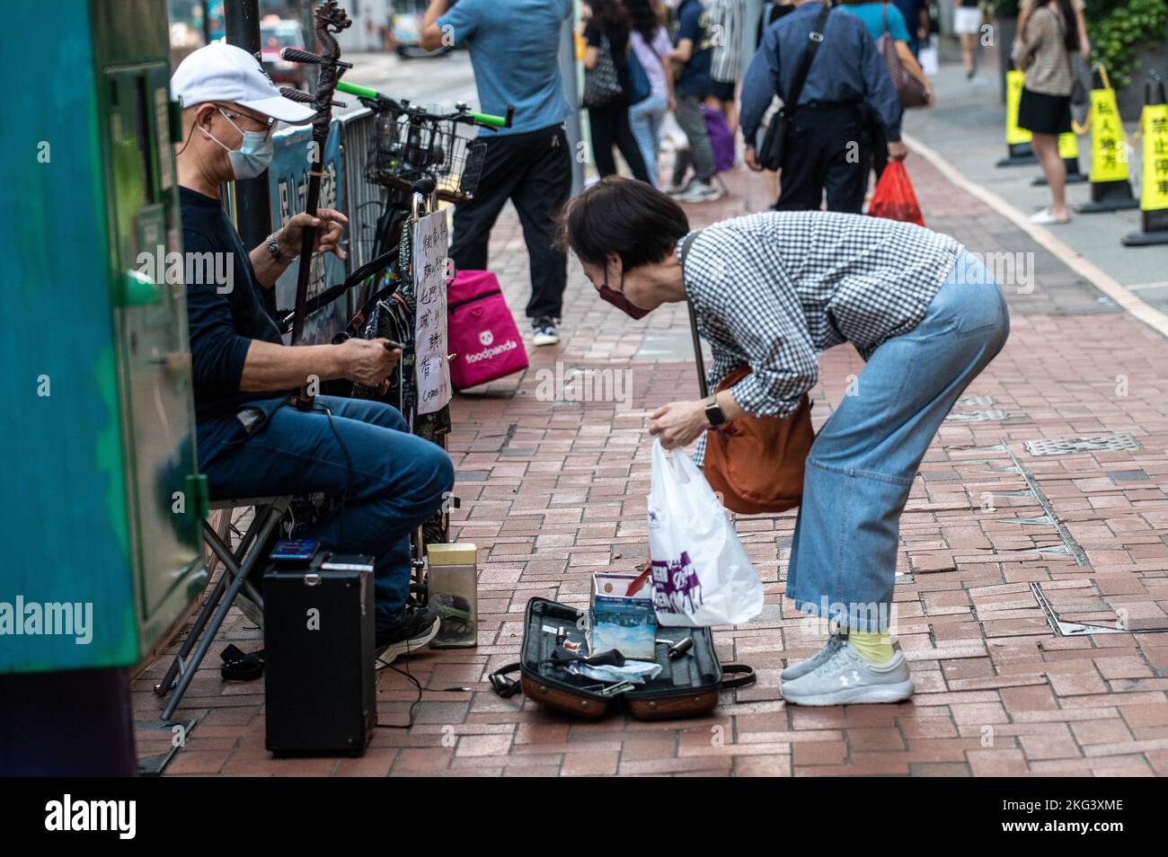 Una donna offre denaro a un musicista che suona 'Glory to Hong Kong' e 'Do you here the People Sing?' Su un erhu di fronte alla Stazione di Quarry Bay a Hong Kong. "Glory to Hong Kong”, considerato un inno non ufficiale delle proteste a favore della democrazia del 2019, ha fatto notizia ultimamente perché è stato scambiato per l'inno nazionale cinese in occasione di numerosi eventi internazionali di rugby. A Hong Kong, permangono dubbi circa la legalità di suonare o di eseguire questa canzone in pubblico ai sensi della legge sulla sicurezza nazionale. (Foto di ben Marans/SOPA Images/Sipa USA) Foto Stock