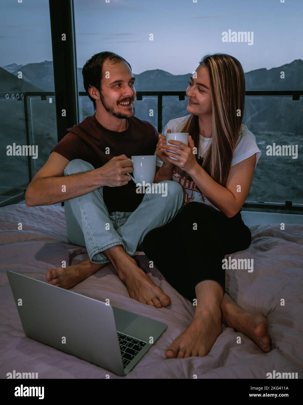 Bella coppia in casa accogliente, seduta sul letto, bere un tè Foto Stock