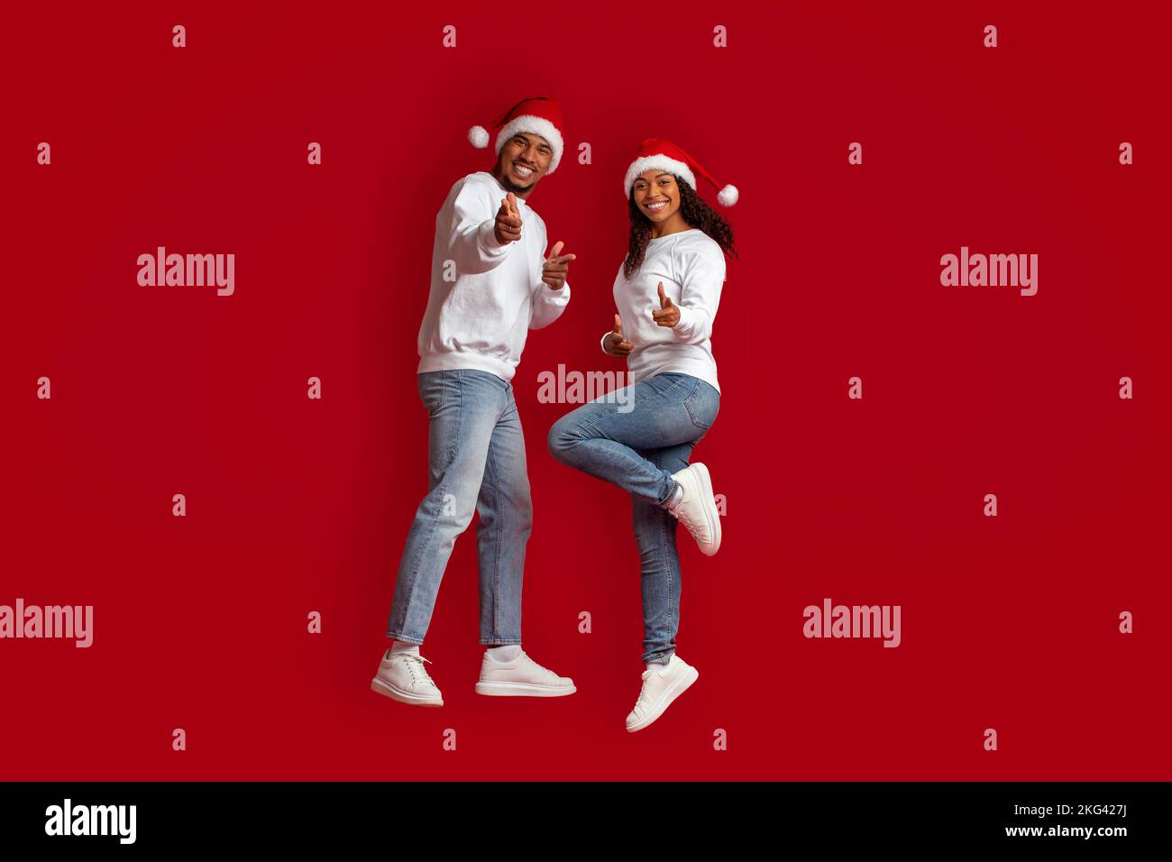 Allegro coppia nera che indica la macchina fotografica sul rosso, celebrando il Natale Foto Stock