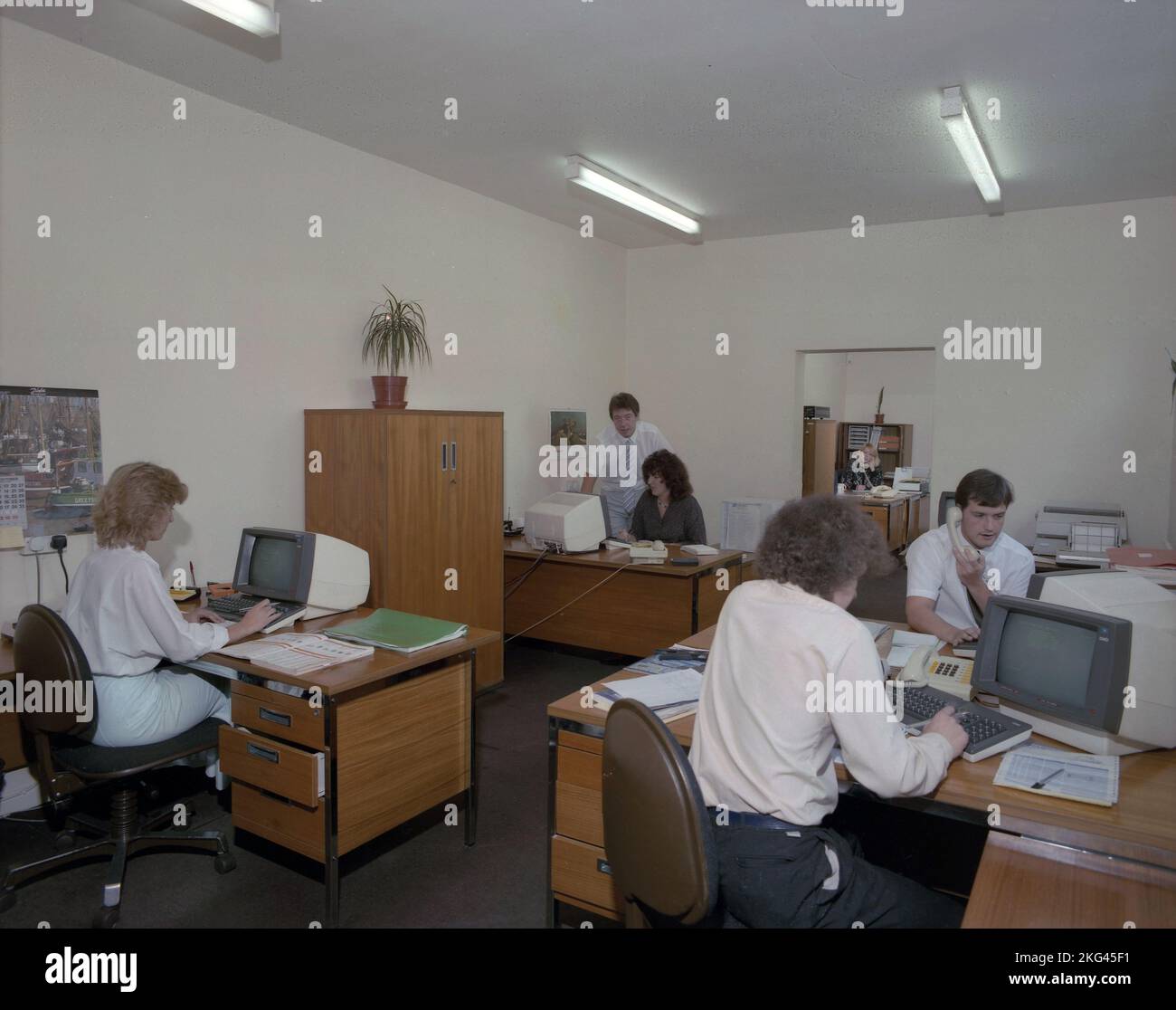 1980s, storici, lavoratori d'ufficio seduti alle scrivanie utilizzando computer terminali di era, Inghilterra, Regno Unito. Foto Stock