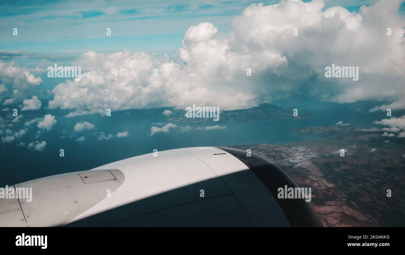 Vista dal Boeing 737 MAX 8 su nuvole bianche, cielo azzurro e superficie della Terra con campi e montagne. Telaio in bianco-grigio con Foto Stock