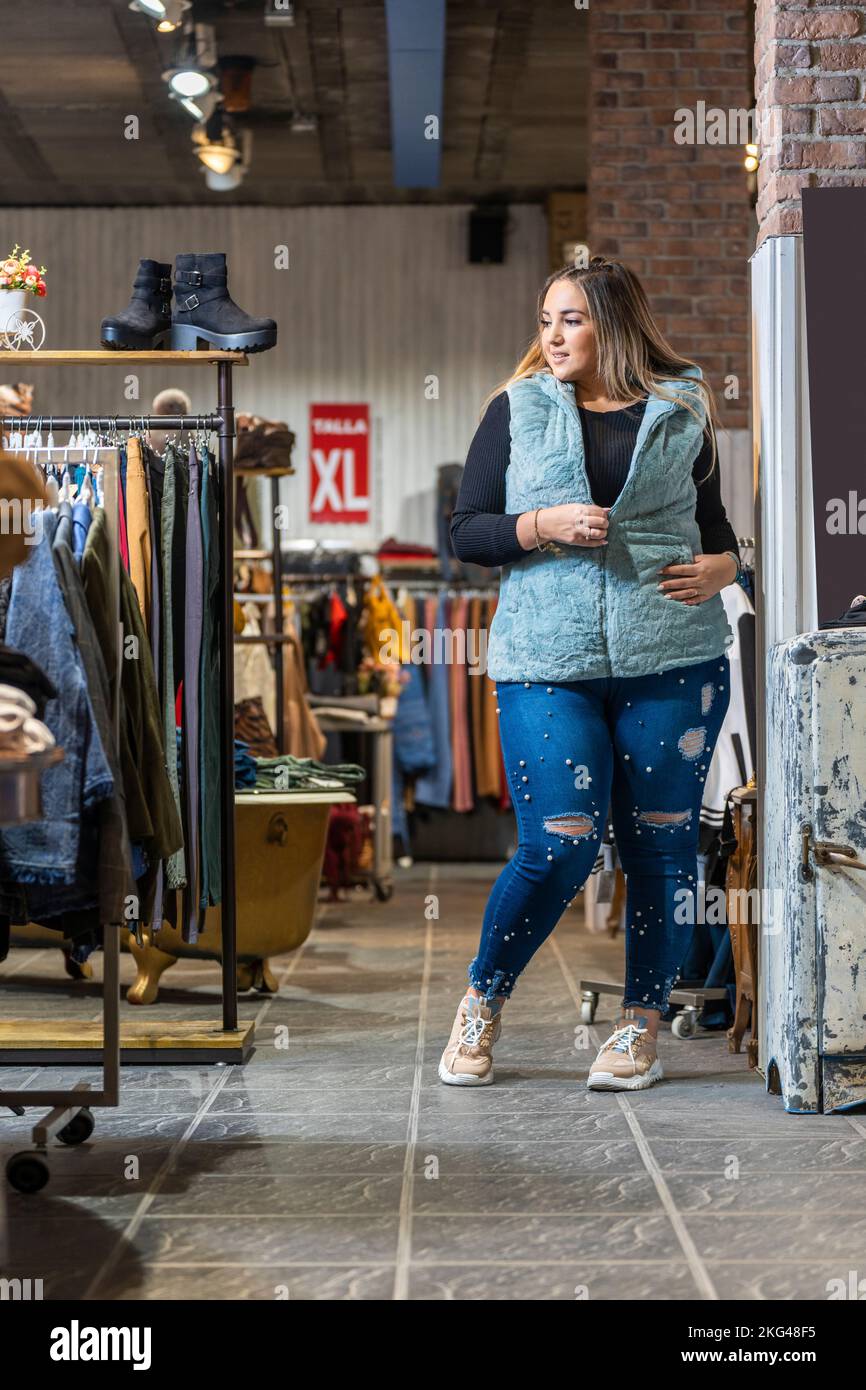 Donna sovrappeso che prova su vestiti in un deposito di vestiti nella sezione più di taglia Foto Stock