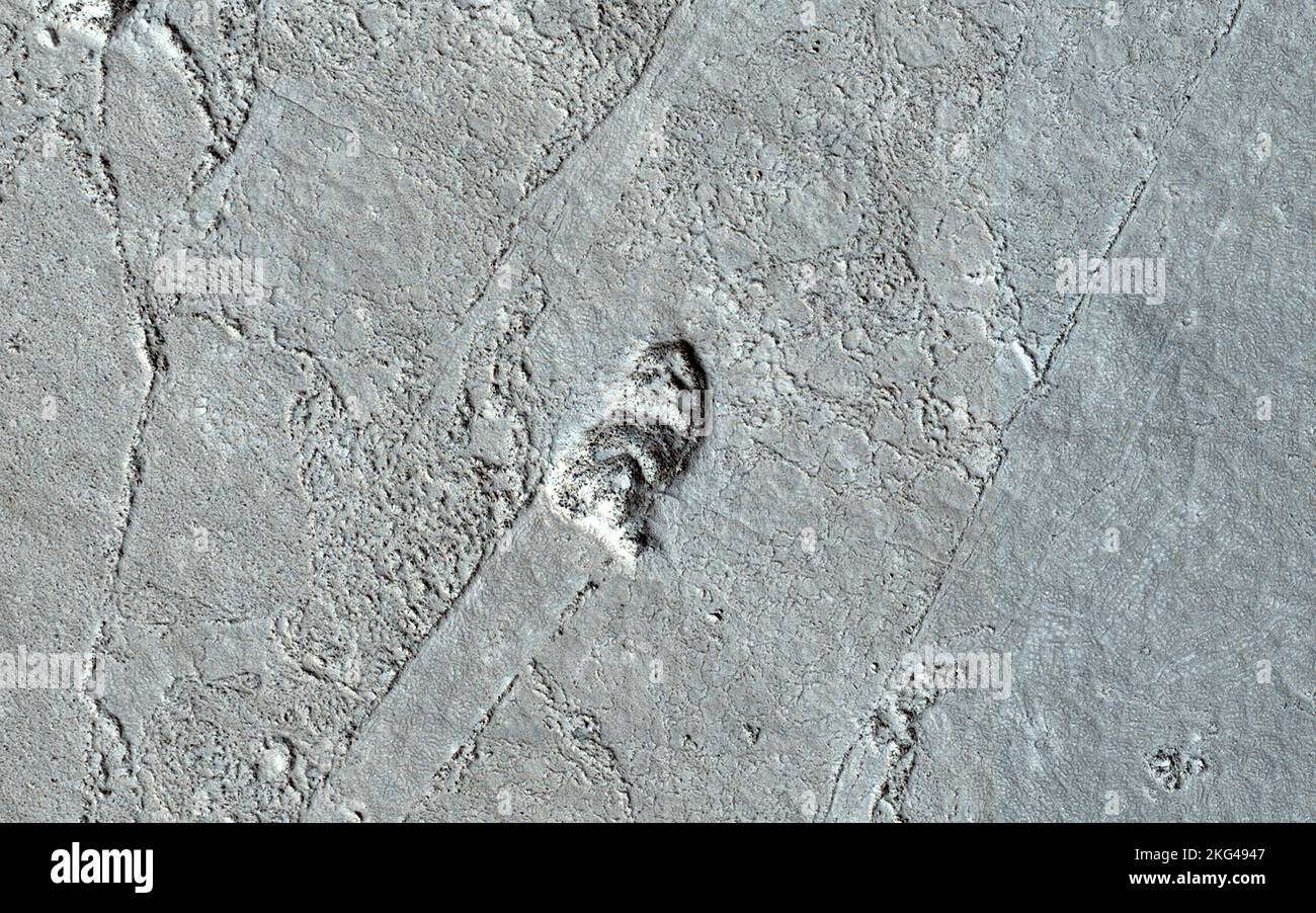 Sulla scia di antichi flussi di lava. Molto tempo fa, un grande flusso di lava passava attraverso la regione di Athabasca Valles di Marte. Possiamo dire in quale direzione stava scorrendo esaminando la superficie del flusso e i rimanenti risvegli lavici. Anche se non è possibile navigare una barca su un mare di lava, colline e crateri che si attaccano più in alto del flusso di lava agiscono come barriere. Quando una barca è guidata attraverso l'acqua, c'è un'onda di prua nella parte anteriore della barca, e una scia che si sposta dietro che indica il modo in cui la barca si muove. In un flusso di lava, quando una collina si attacca, la lava si accumula sul lato a monte (solo Foto Stock