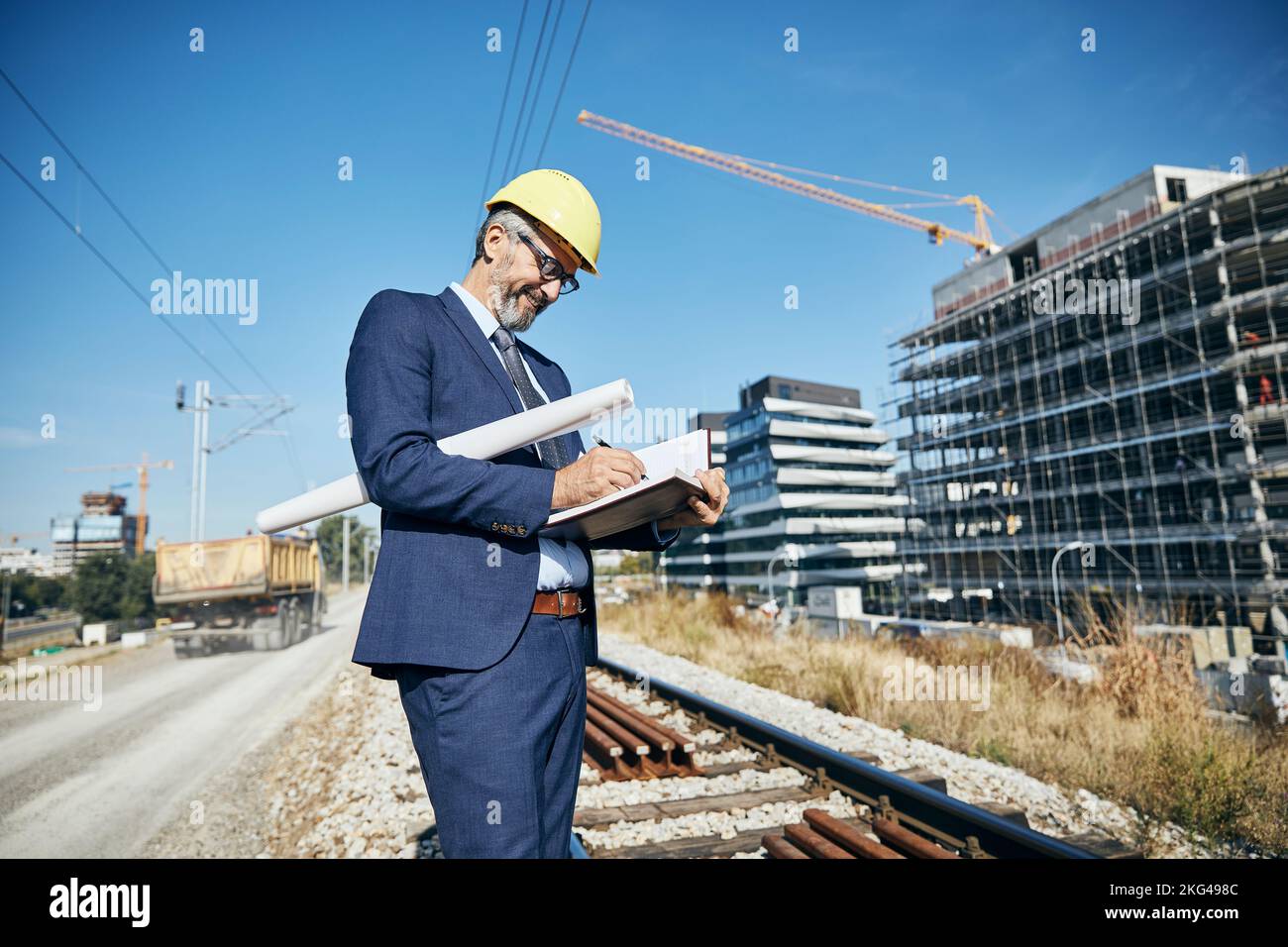 senior businessman architetto casco costruzione sito costruzione architettura scrittura notebook protettivo workwear piano blueprint Foto Stock