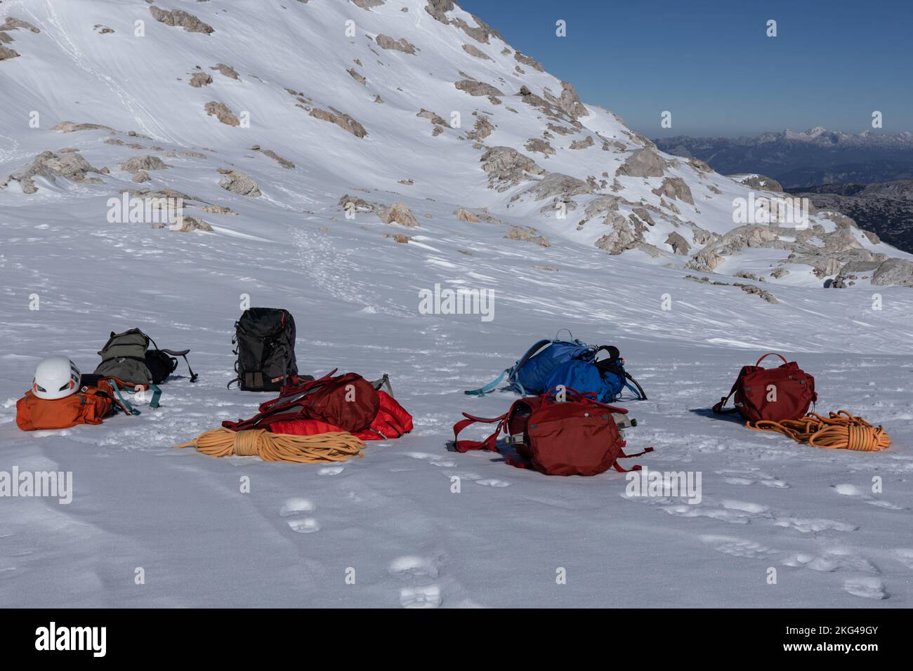 Attrezzatura da arrampicata - zaini colorati, corde, caschi si trovano su una pista innevata, Austria, Alpi, Dachstein Foto Stock
