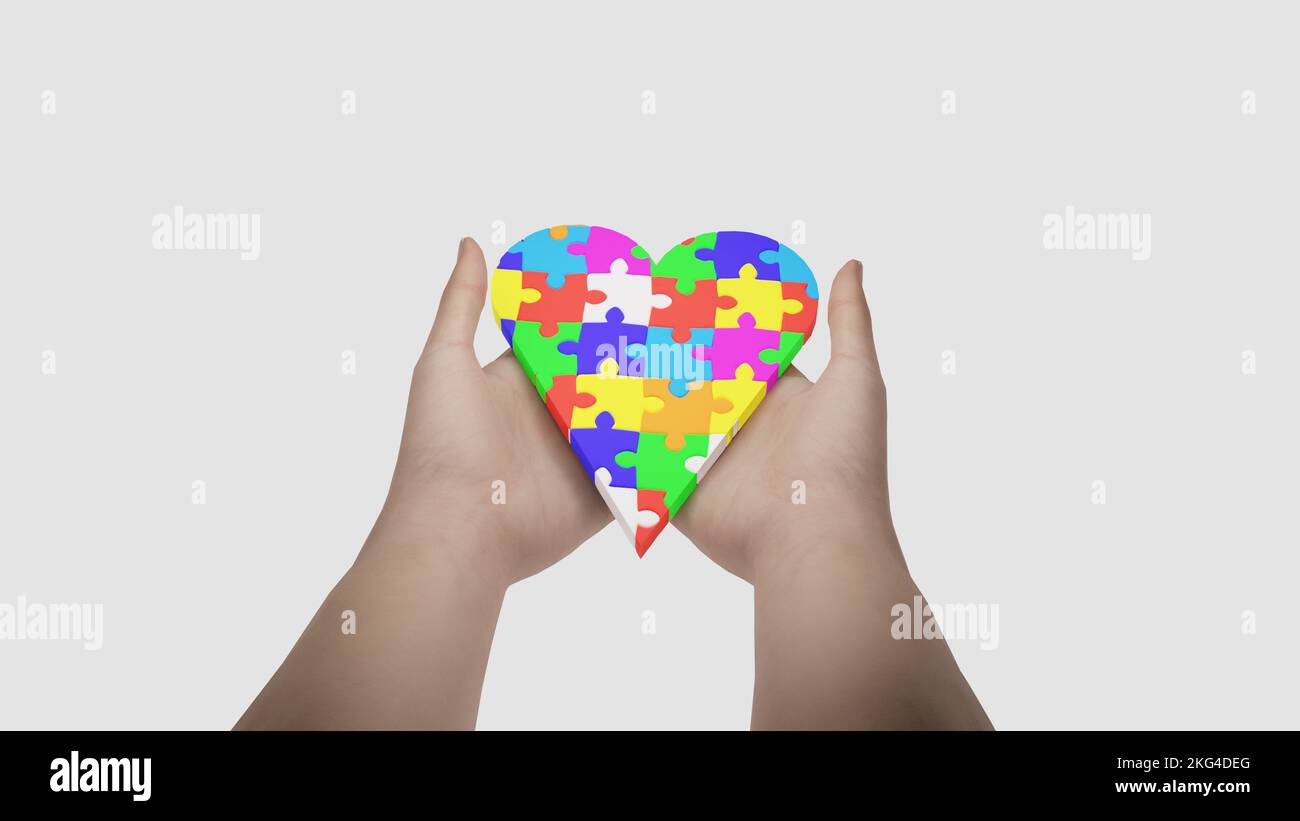 Il simbolo dell'autismo è un puzzle multicolore sotto forma di cuore nelle mani di genitori premurosi. Cura e amore per i bambini disor spettro autismo Foto Stock