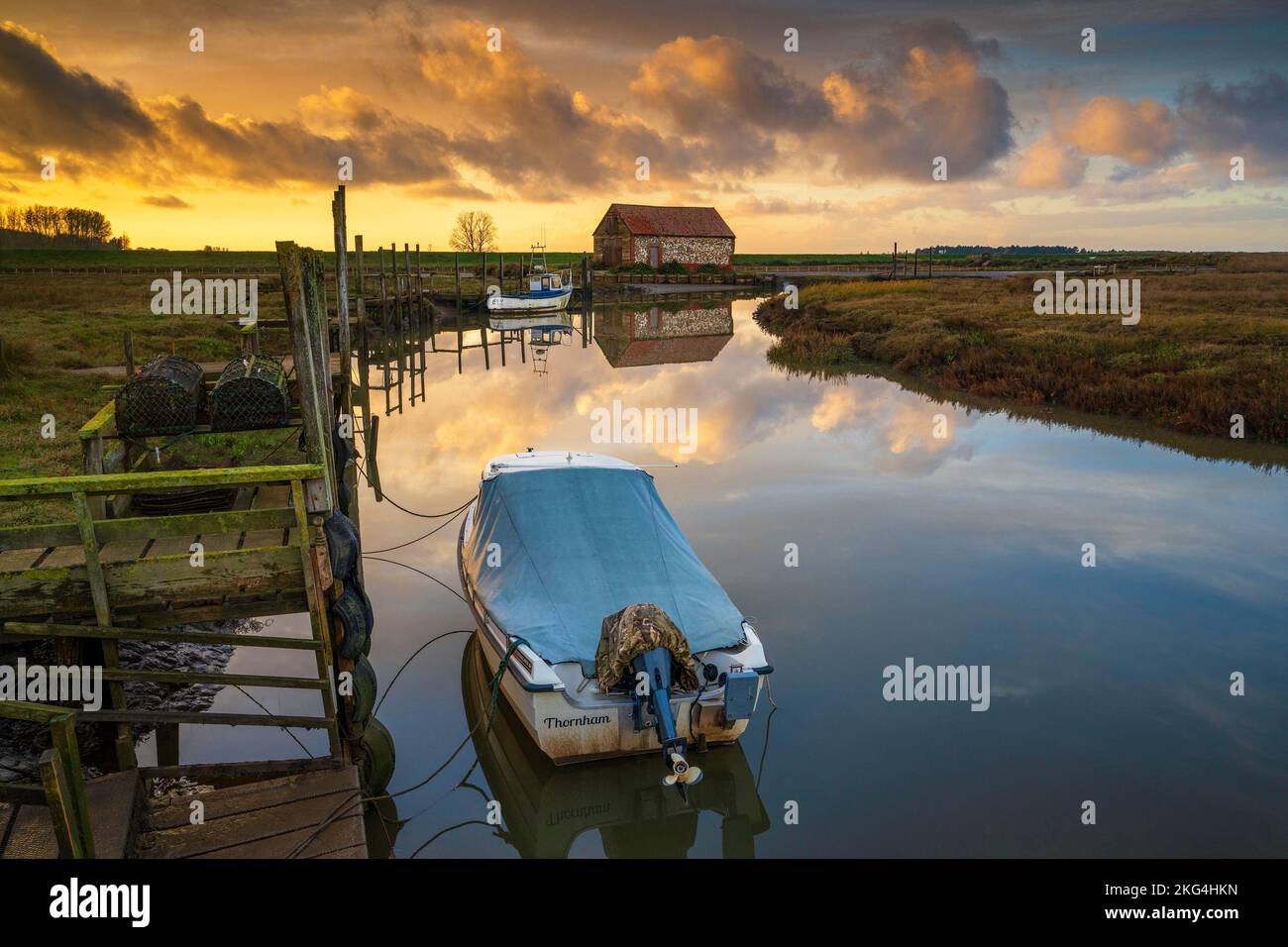 Barche e fienile di carbone sull'estuario a Thornham Old Harbour al tramonto, Thornham, Norfolk, Inghilterra Foto Stock