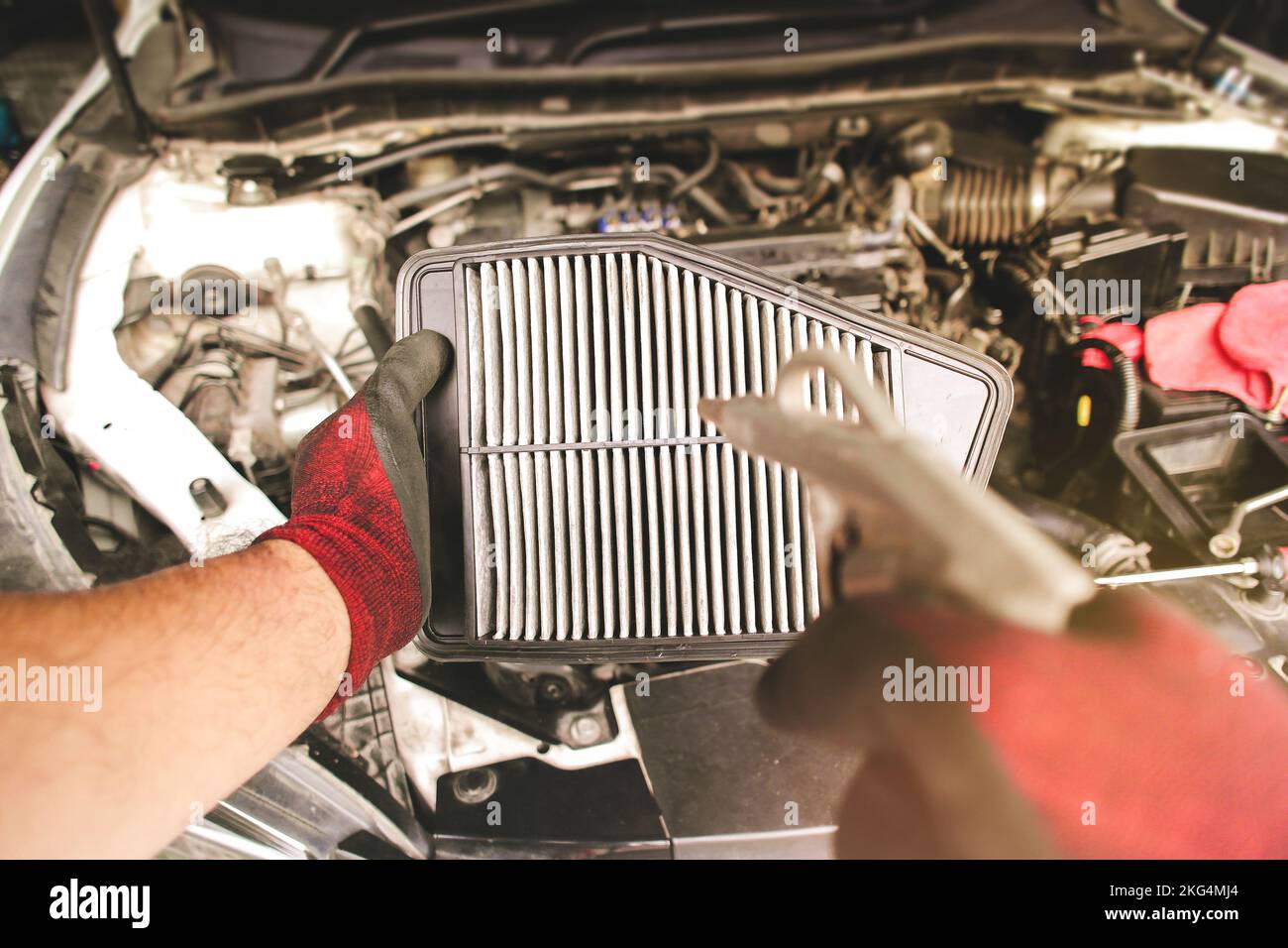 Il filtro dell'aria dell'auto nella mano meccanica automatica soffia la polvere e pulisce con la pistola ad aria compressa Foto Stock