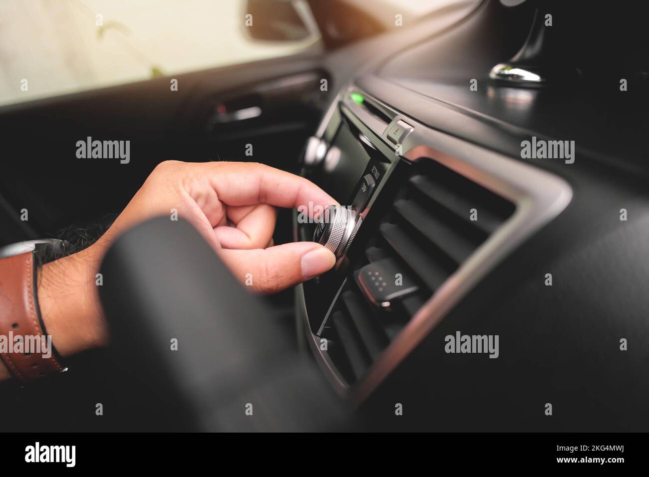 La mano del conducente regola il volume sul cruscotto dell'autoradio. Foto Stock
