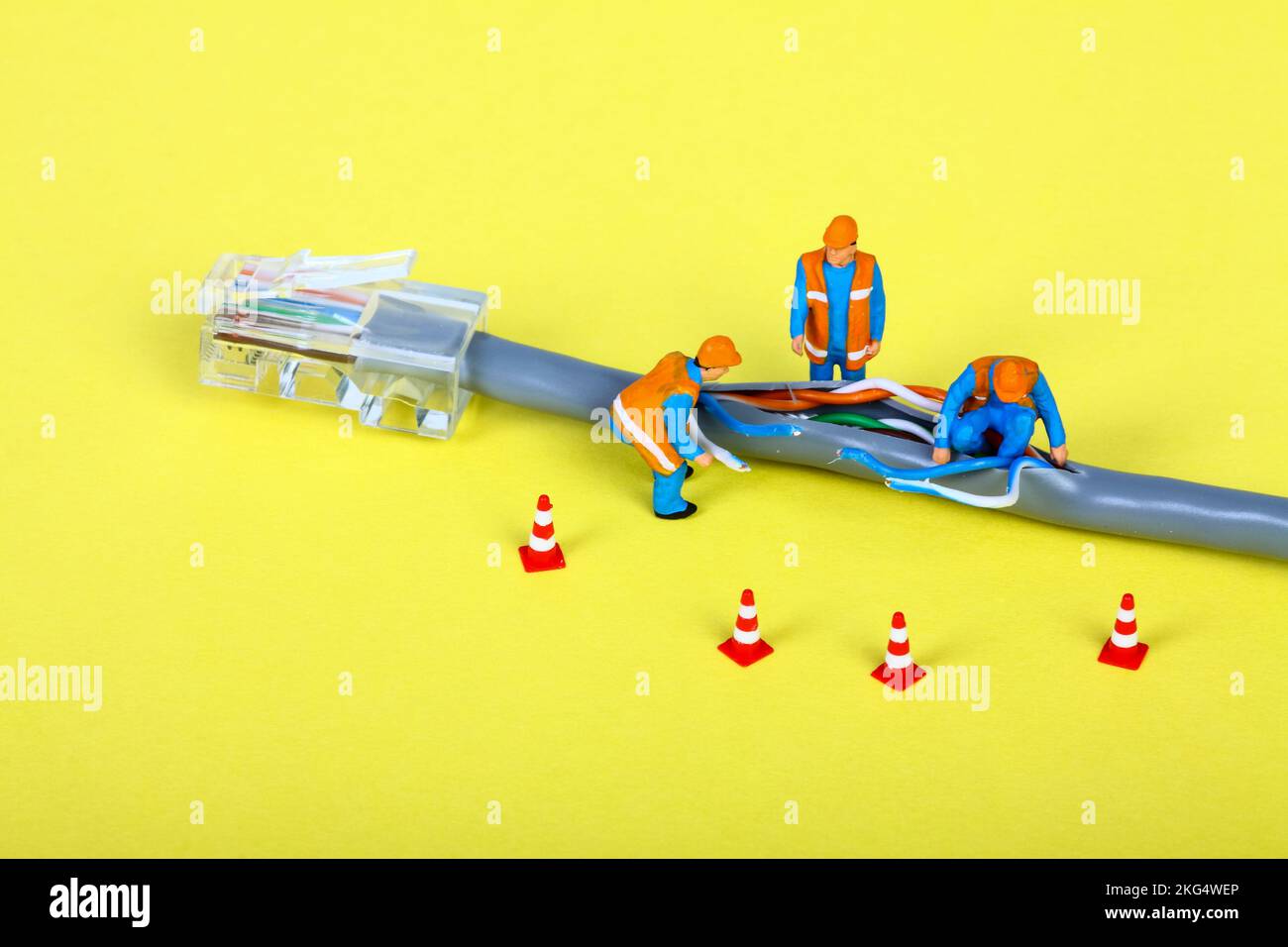 Immagine concettuale di figure in miniatura che indagano su un guasto di un cavo di rete a banda larga Foto Stock