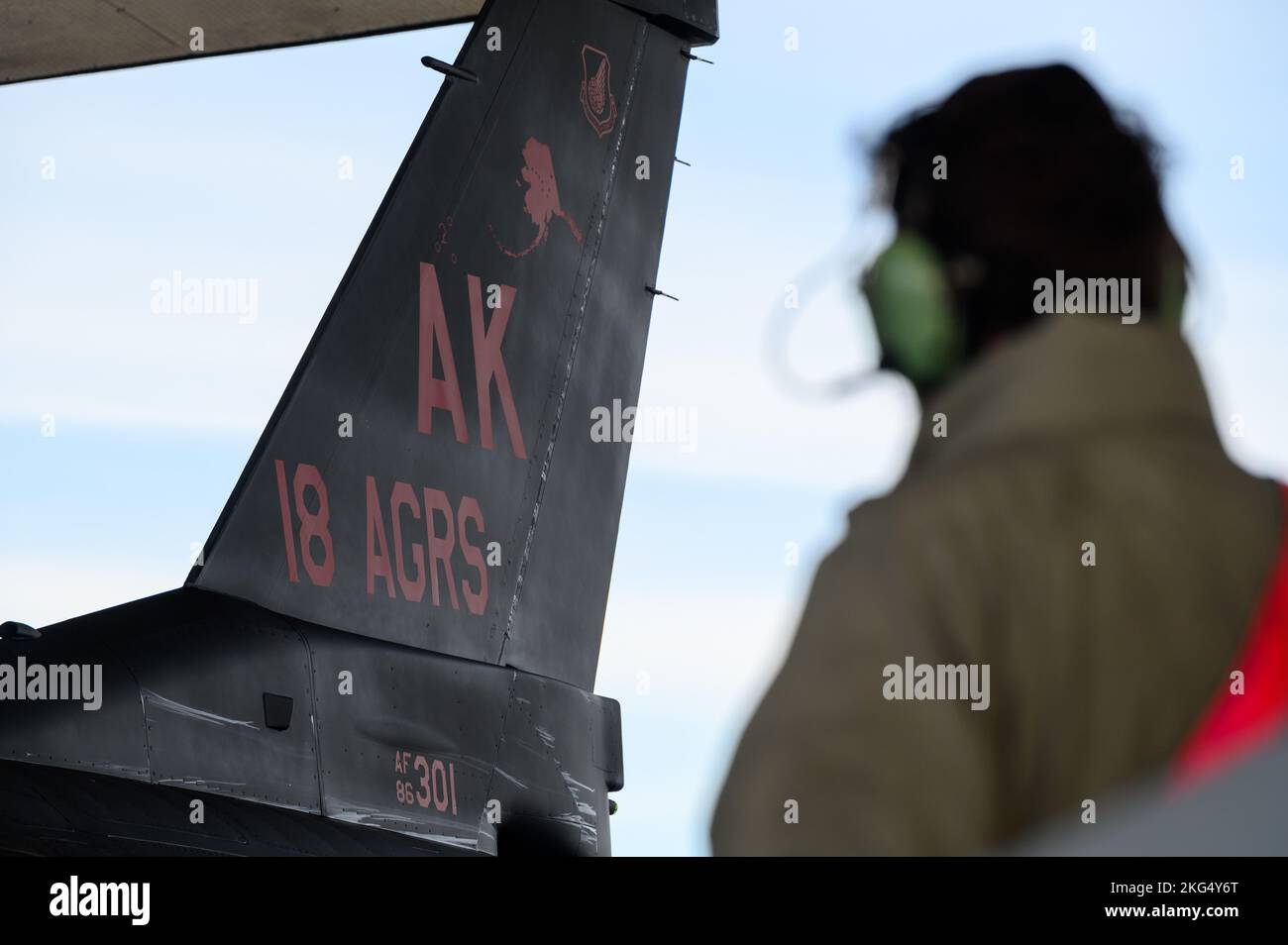 Un capo dell'equipaggio dell'aeronautica degli Stati Uniti assegnato all'unità di manutenzione dell'aeromobile 18th esegue operazioni di recupero su uno squadrone Aggressor 18th F-16 Fighting Falcon presso la base dell'aeronautica militare di Eielson, Alaska, 29 ottobre 2022. Questa è la prima volta che Eielson avrà lo schema di verniciatura dell'aggressore di wraith nel suo inventario aereo. Foto Stock