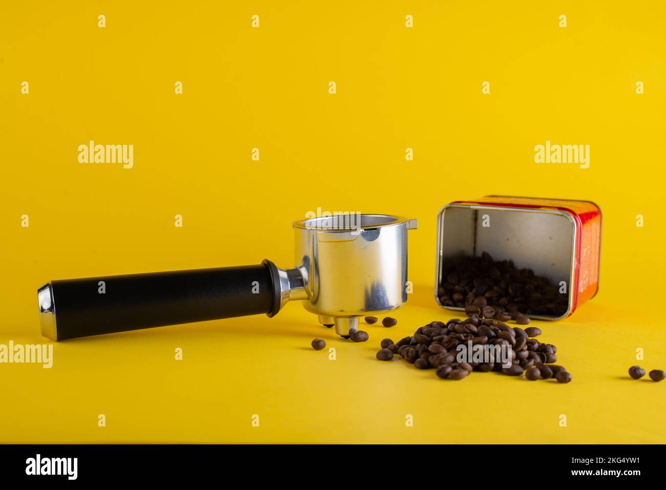 Chicchi di caffè e confezione con portafiltro su sfondo giallo Foto Stock