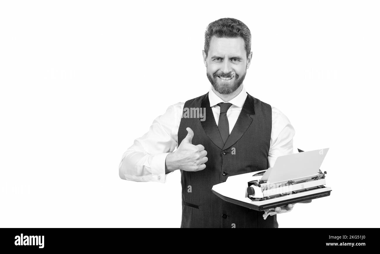 felice uomo d'affari tenere retrò typewriter e mostrare pollice su isolato su bianco, litterateur Foto Stock