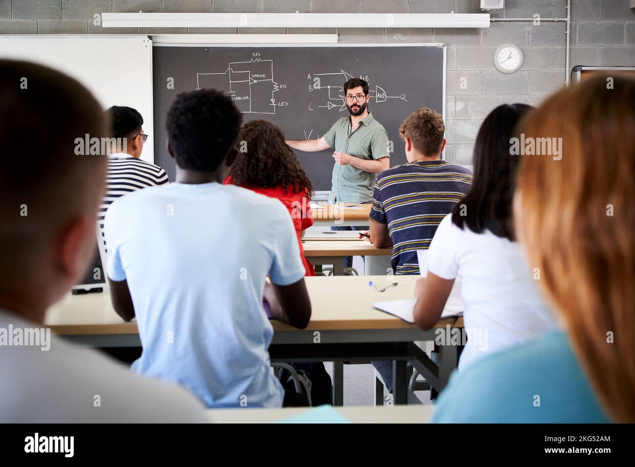 Insegnante di sesso maschile studenti universitari in aula. Vista posteriore dal college che frequenta un insegnante in classe. Il professore spiega la lezione su Foto Stock