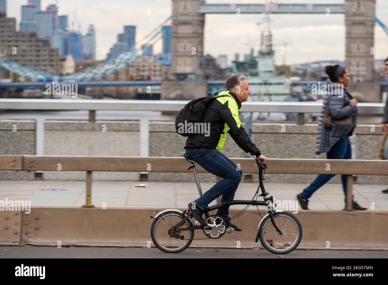 Un uomo che si sposti durante l'ora di punta su una bicicletta pieghevole Brompton attraverso London Bridge, Londra, Regno Unito. 18 Nov 2022 Foto Stock