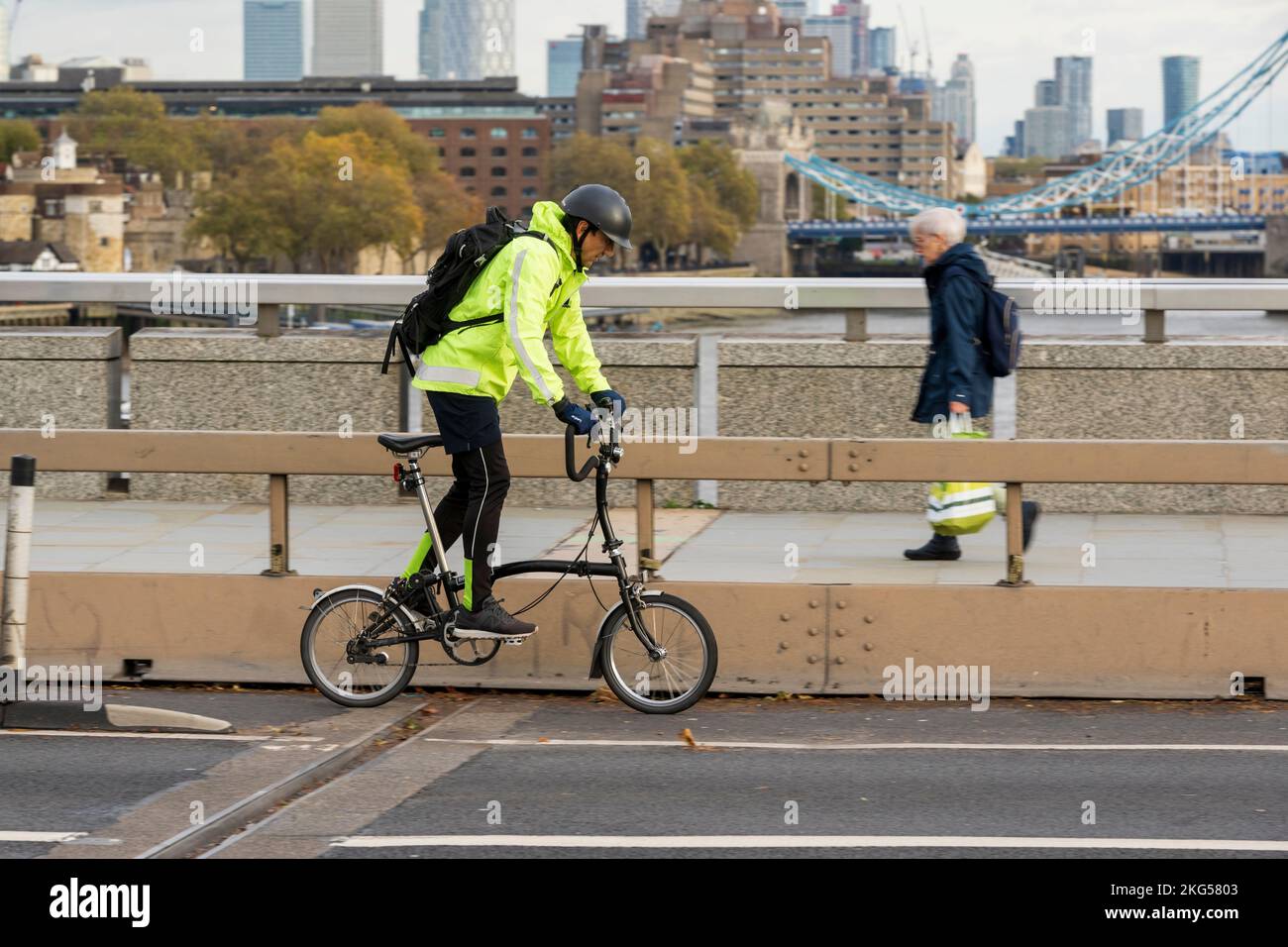 Un uomo che si sposti durante l'ora di punta su una bicicletta pieghevole Brompton attraverso London Bridge, Londra, Regno Unito. 17 Nov 2022 Foto Stock