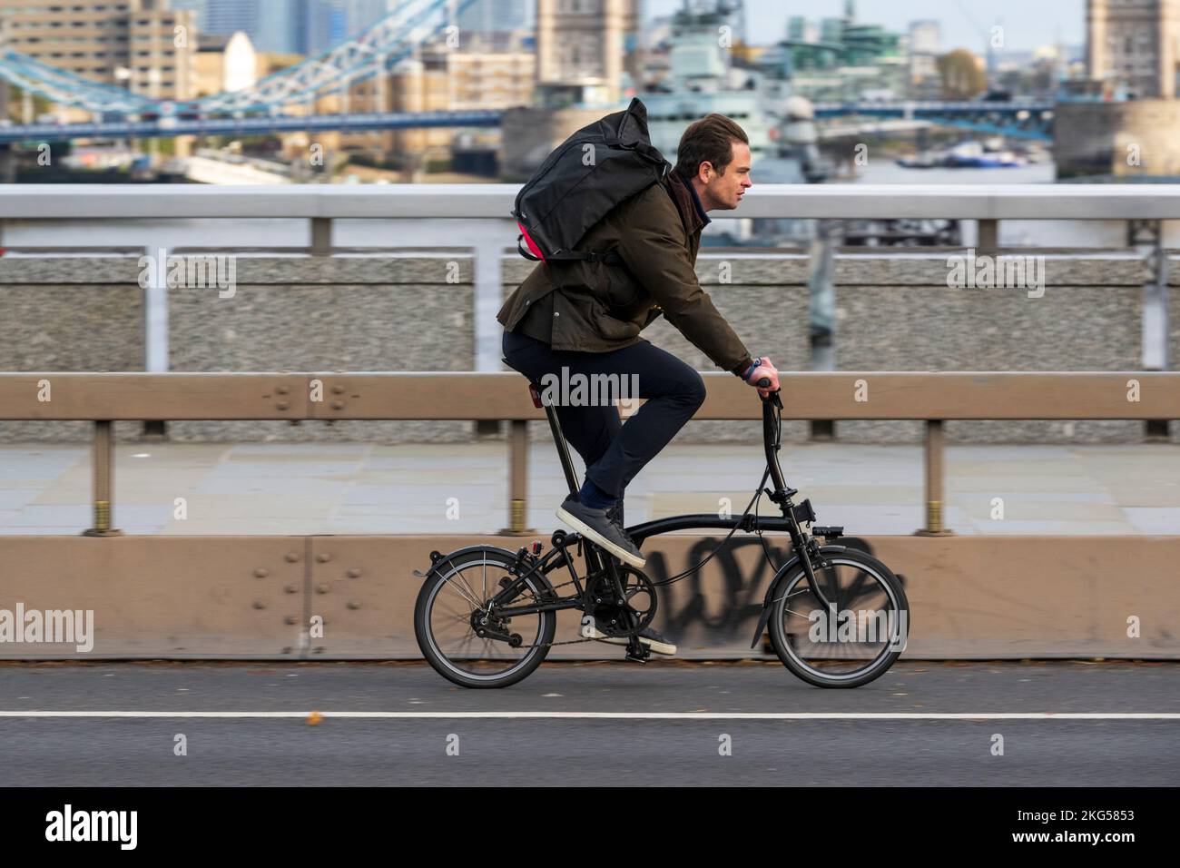 Un uomo che si sposti durante l'ora di punta su una bicicletta pieghevole Brompton attraverso London Bridge, Londra, Regno Unito. 17 Nov 2022 Foto Stock