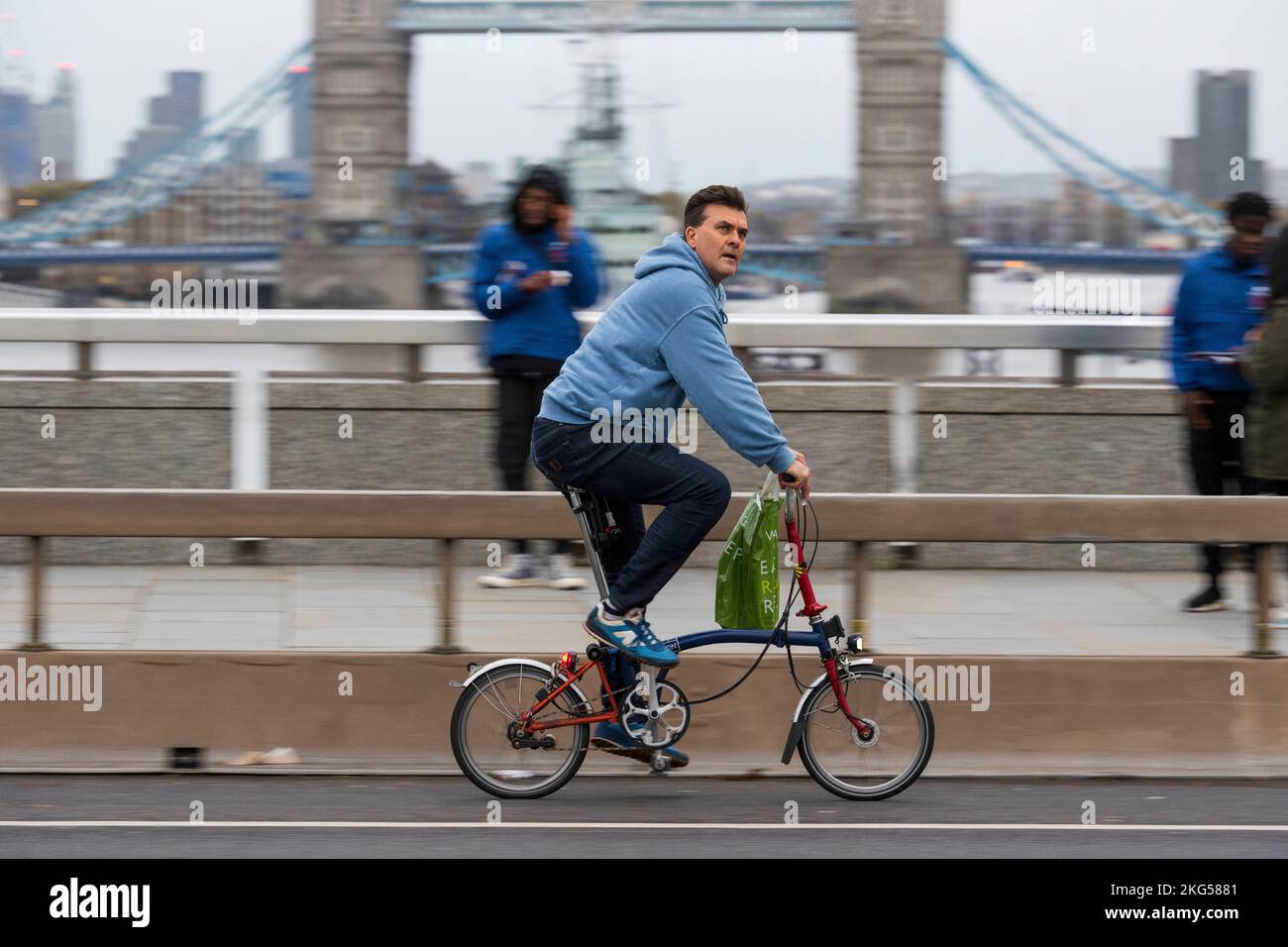 Un uomo che si trova in viaggio durante l'ora di punta su una bicicletta pieghevole Brompton attraverso London Bridge, Londra, Regno Unito. 16 Nov 2022 Foto Stock