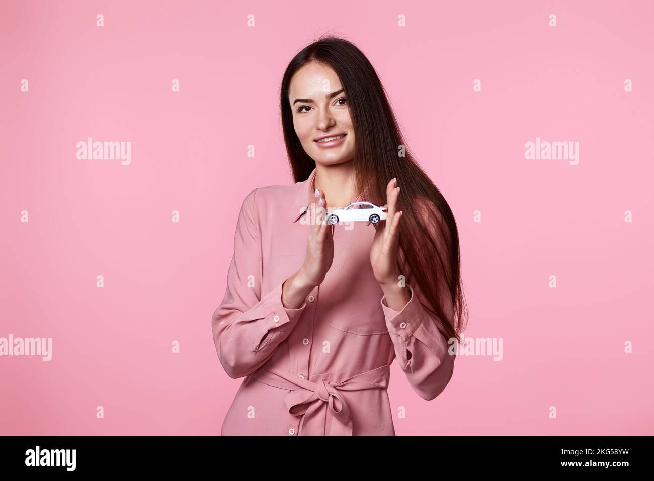 bella donna in vestito tenendo piccola auto bianca Foto Stock