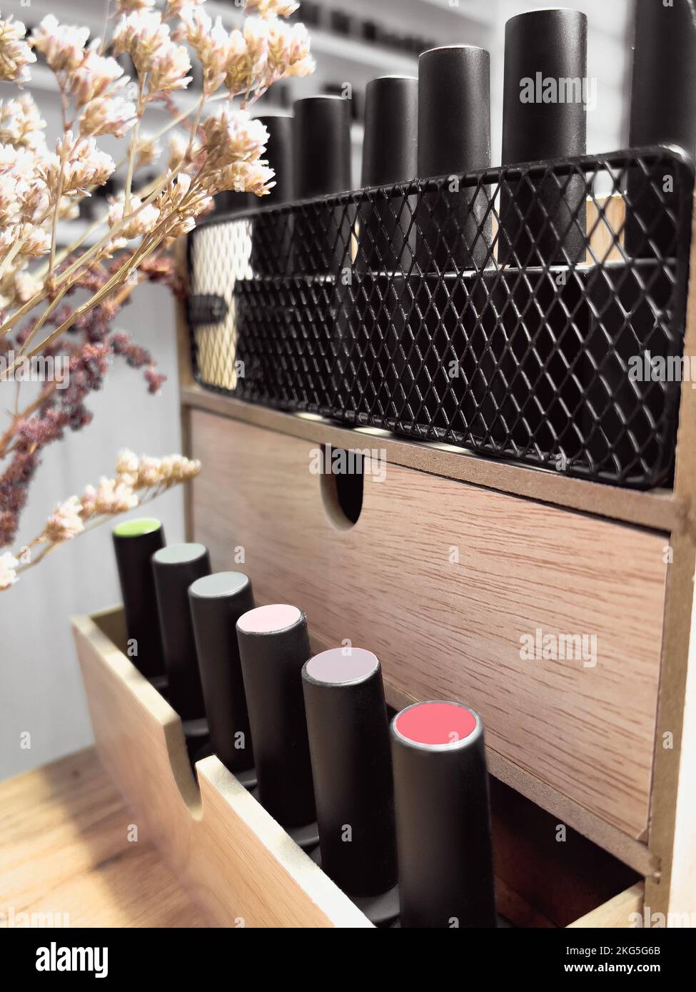 Bottiglie nere di smalto per unghie su fondo legno con fiori Foto Stock