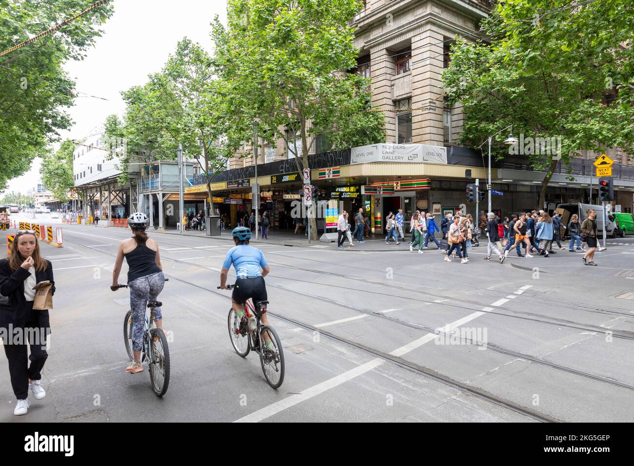 Donne ciclisti che indossano caschi cavalcano le loro biciclette nel centro di Melbourne, indossando abiti da ginnastica, Victoria, Australia Foto Stock