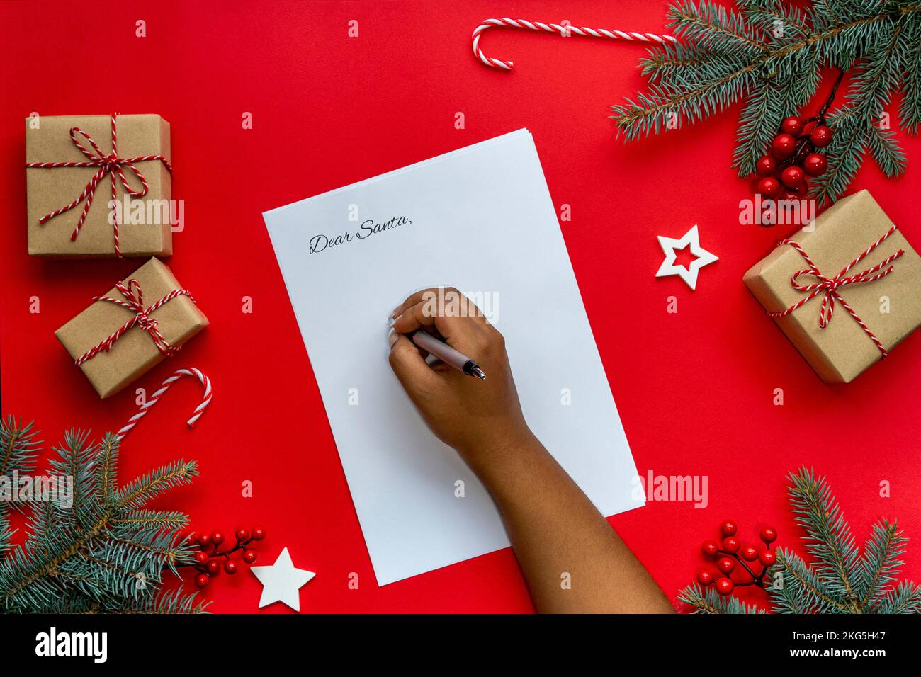 Le mani della donna che scrivono la lettera a Santa su una priorità bassa di decorazione di Natale Foto Stock