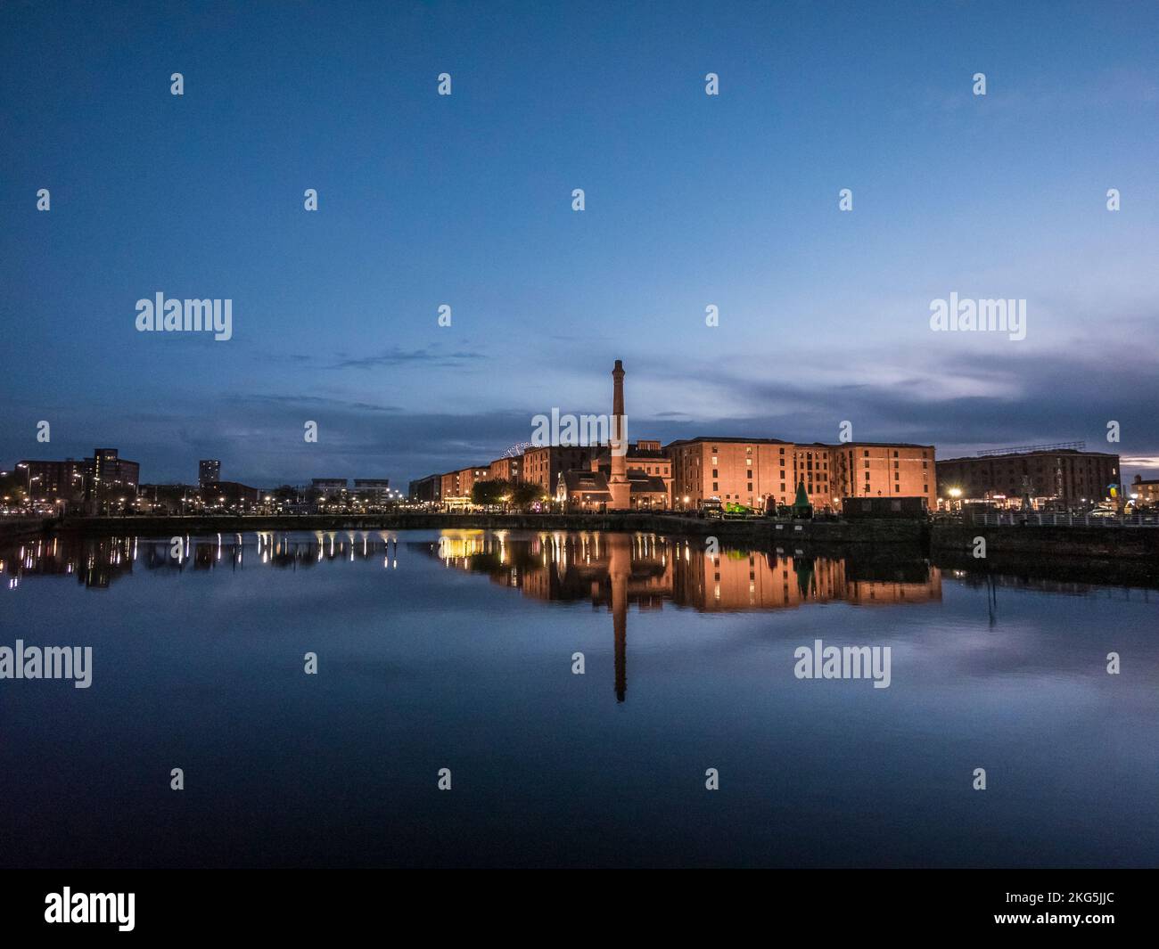 Scena notturna di strada nella città portuale di Liverpool visto qui all'Albert Dock guardando attraverso il pontile al vecchio camino del molo pompa casa Foto Stock