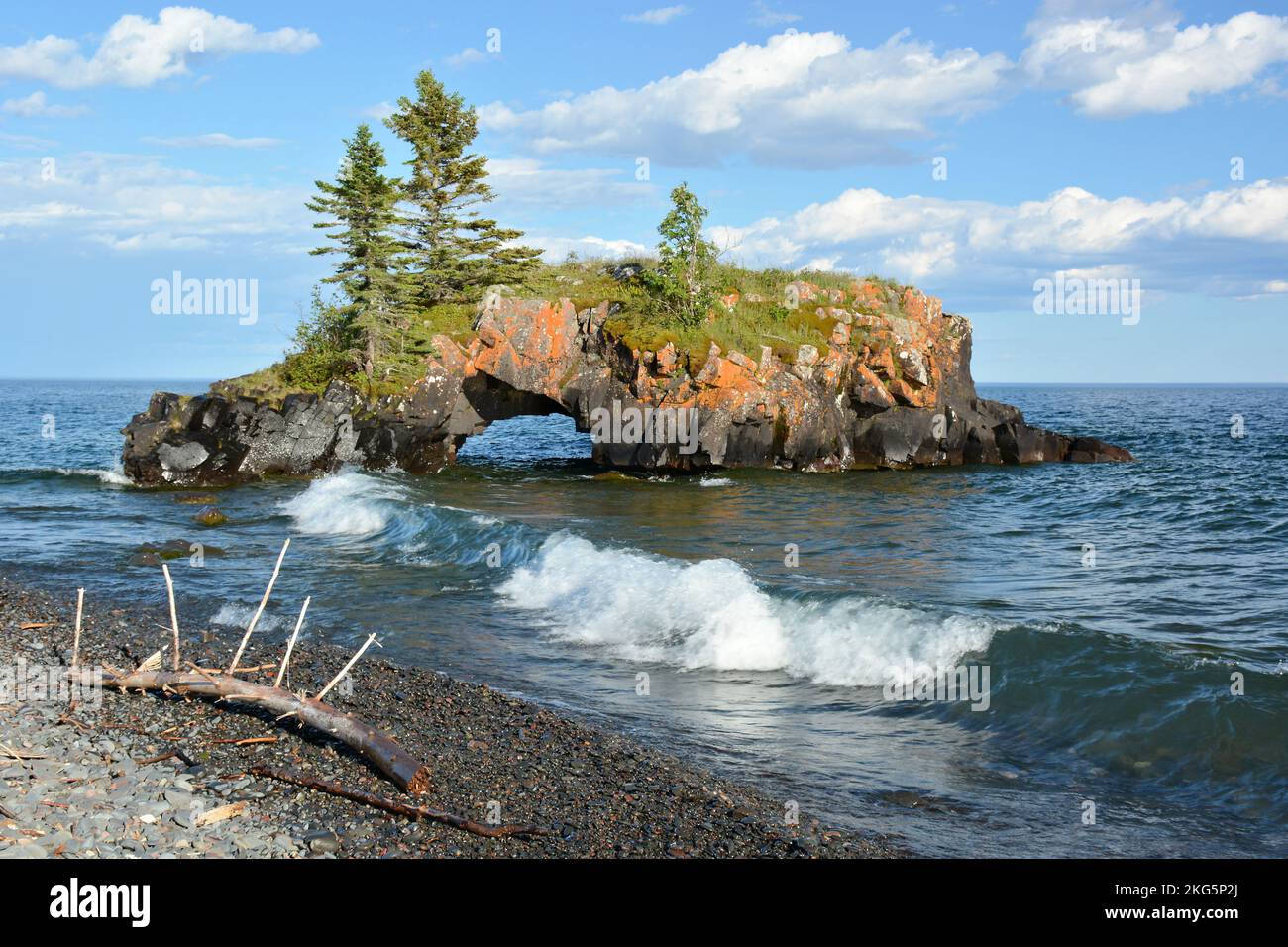 I demolitori che si tuffano dal sole si surclassano davanti a un isolotto roccioso e scavato nel lago Superior Foto Stock