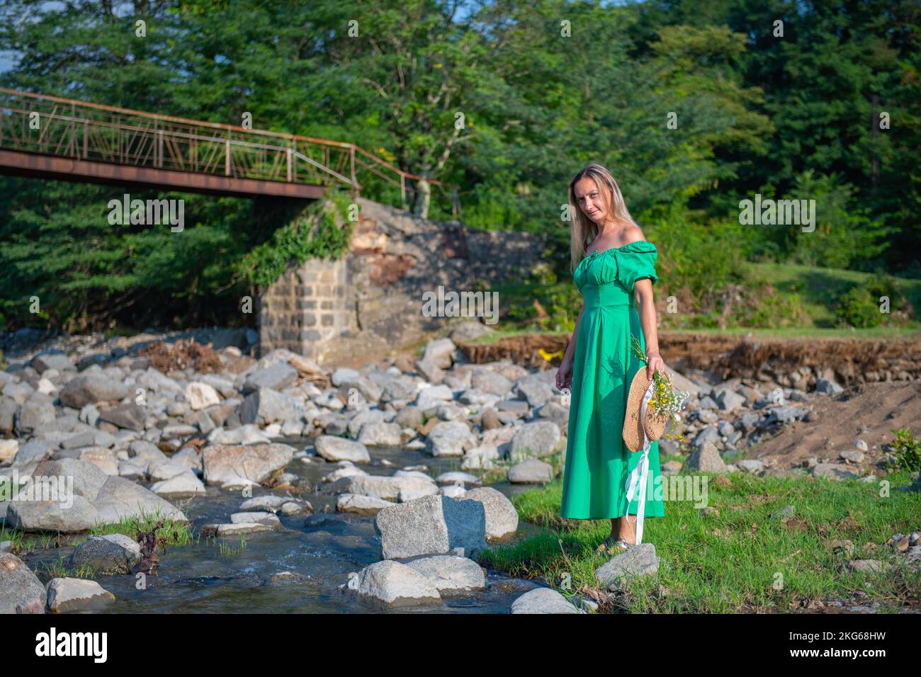 una ragazza in un vestito verde è in piedi presso il fiume Foto Stock