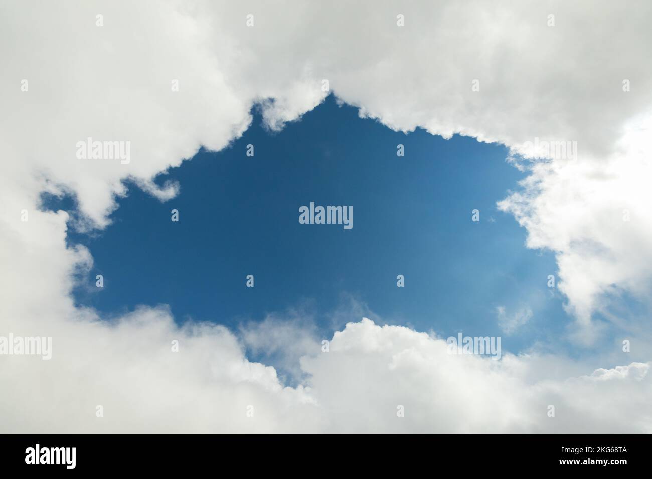 Un pezzo di cielo blu circondato da nuvole bianche Foto Stock