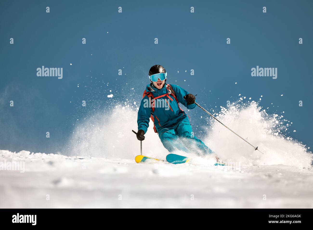 Lo sciatore maschile veloce corre in discesa sulle piste da sci e getta molta neve Foto Stock