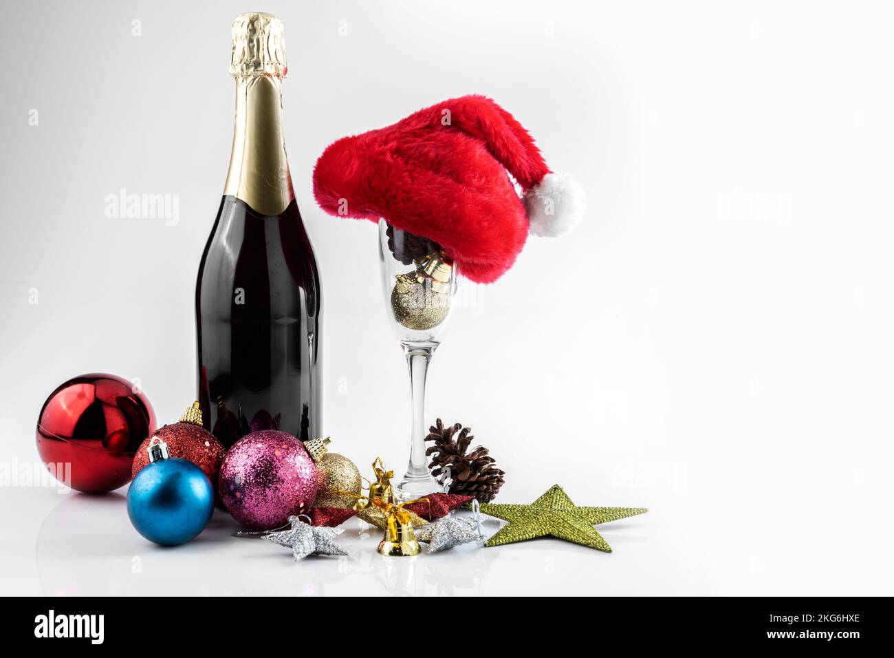Bottiglia di champagne con cappello di Santa e bicchiere di champagne con decorazioni natalizie su sfondo bianco Foto Stock