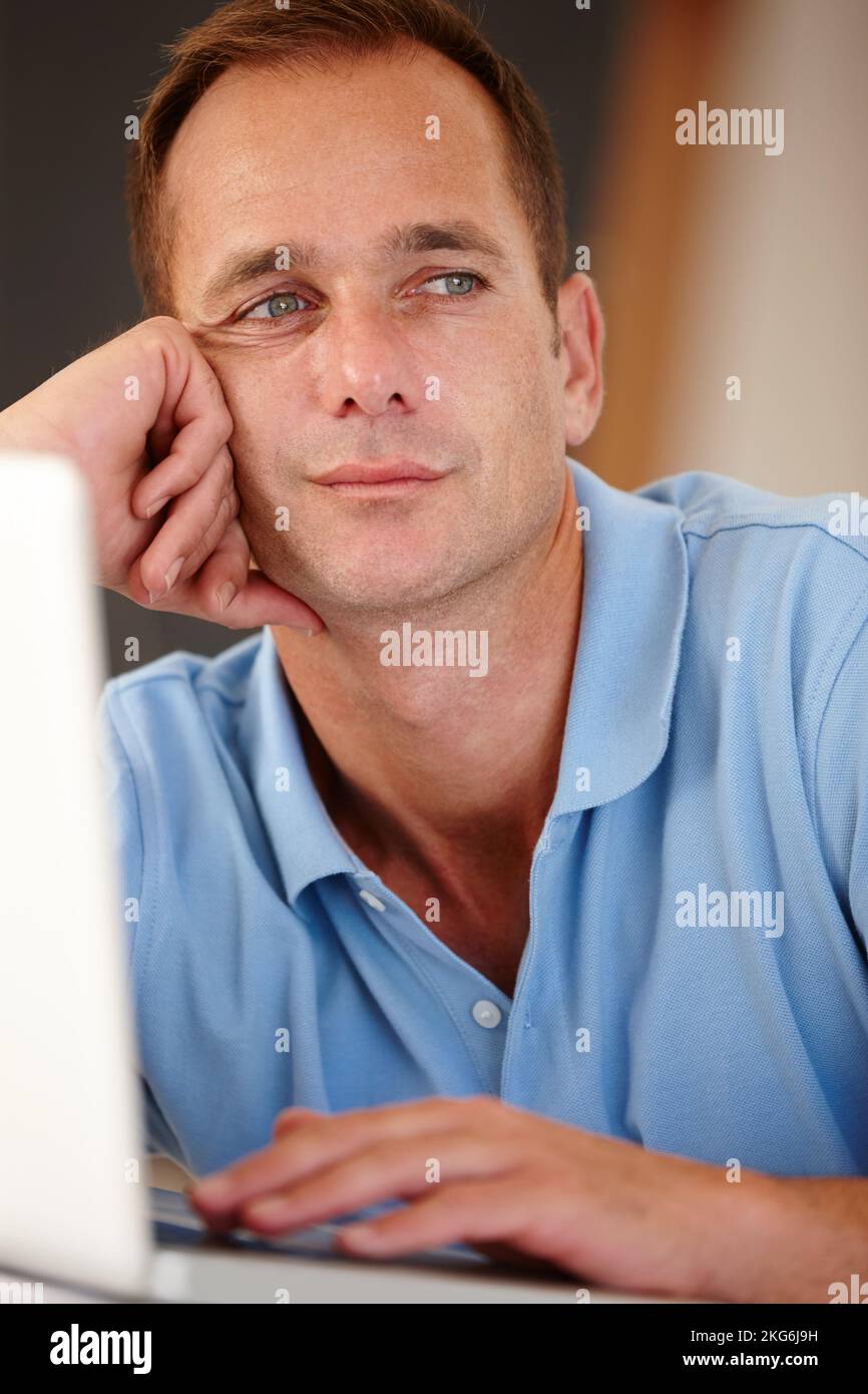 Aggiornamento dello stato... pensiero. L'uomo d'affari guarda attentamente in lontananza mentre lavora sul suo notebook. Foto Stock