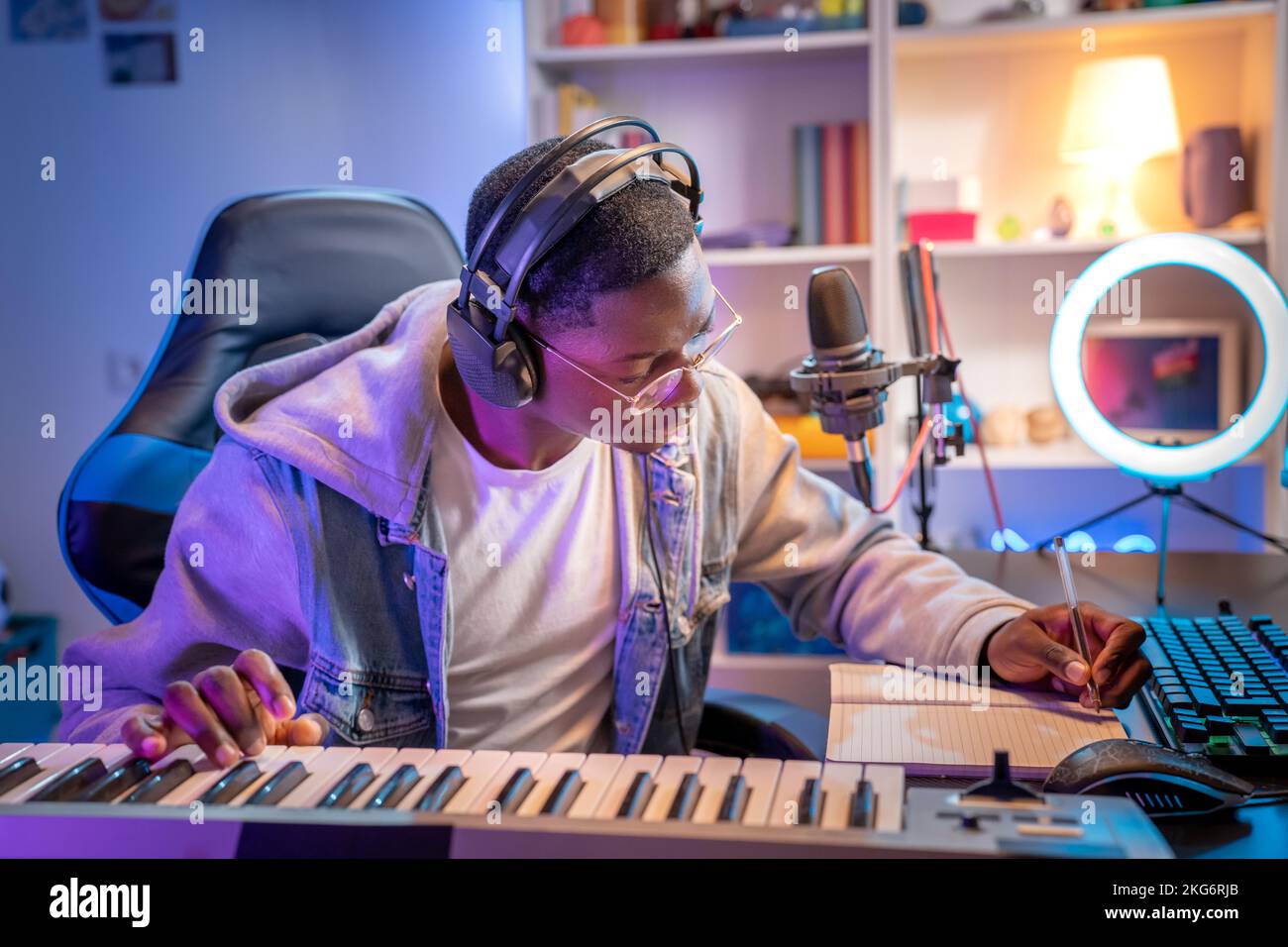 Artista black man che registra musica mentre suona il pianoforte elettronico nello studio di casa. Foto Stock