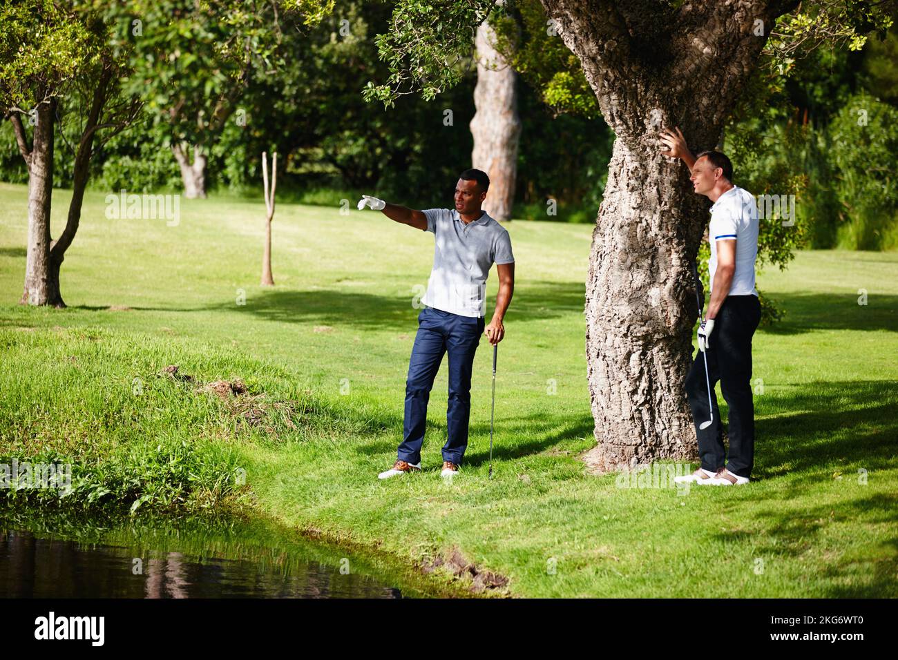 Tracciando il tracciato migliore. due uomini in piedi ad un pericolo d'acqua cercando di capire dove la sfera di golf è. Foto Stock