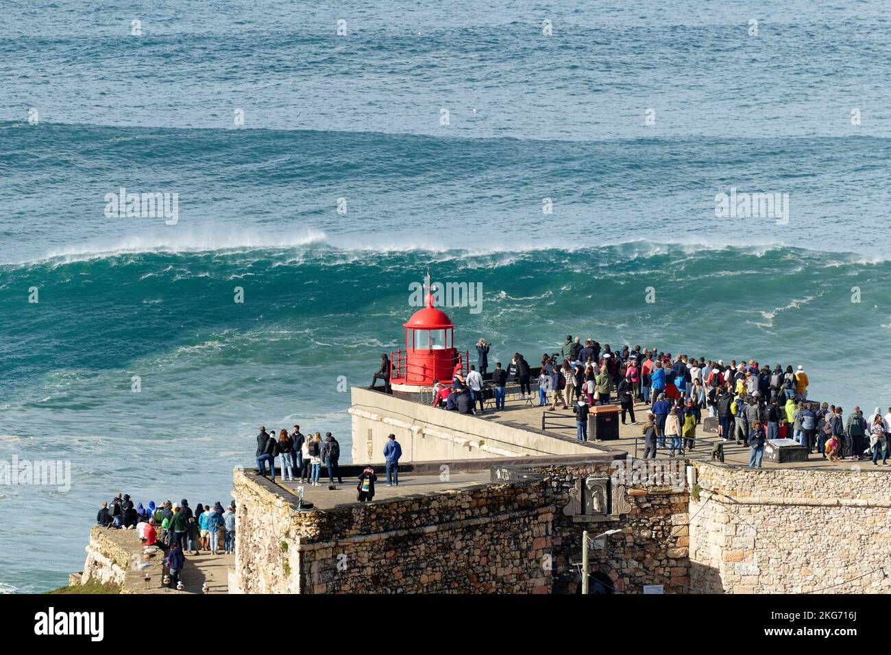 Persone che guardano le grandi onde giganti vicino al Forte di Nazare Lighthouse a Nazare, Portogallo. Le onde più grandi del mondo. Destinazione turistica. Foto Stock