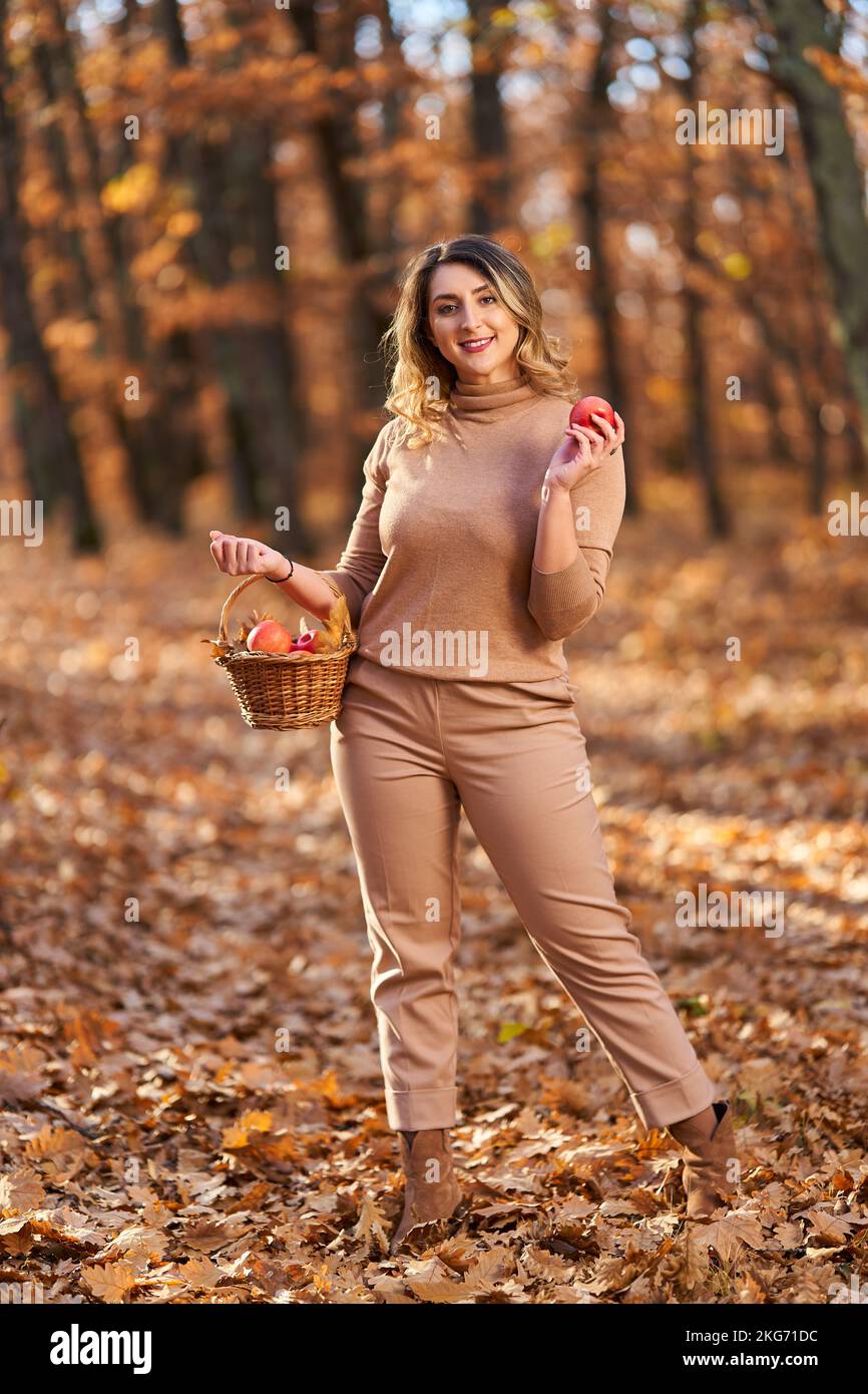 Più dimensione felice bella donna nella foresta di querce in autunno, con un cesto di mele per picnic Foto Stock