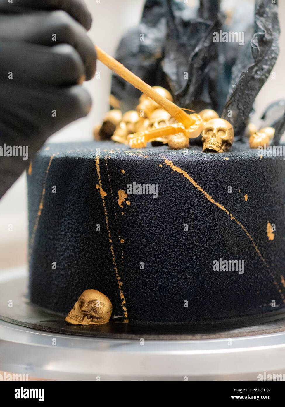 pasticciere finendo horror nero torta di compleanno muertos decorazione con teschi commestibili dorati e vele di carta di riso nero Foto Stock