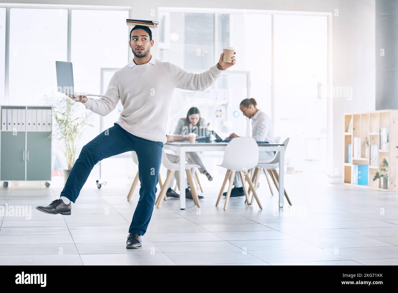 Bilanciate, svolgendo attività in multitasking e occupate con un uomo d'affari che trasporta un computer portatile, una libro e un caffè nella sala riunioni. Assistente, sovraccarichi e una gamba con un maschio Foto Stock