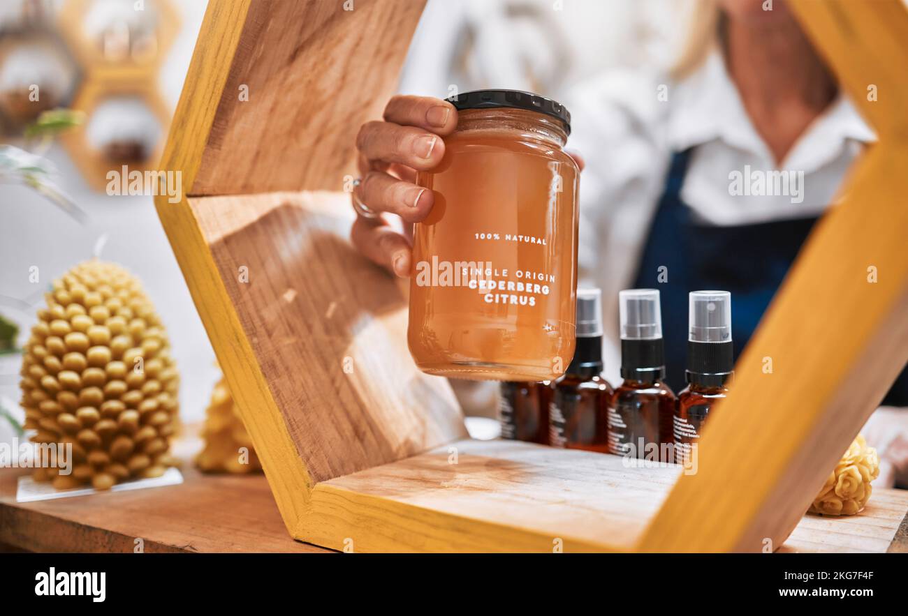 Miele, prodotto e vendita al dettaglio con mani di donna e scaffale espositore per alimentari, alimenti naturali e salutari. Benessere, commerciante e biologico con la piccola impresa Foto Stock