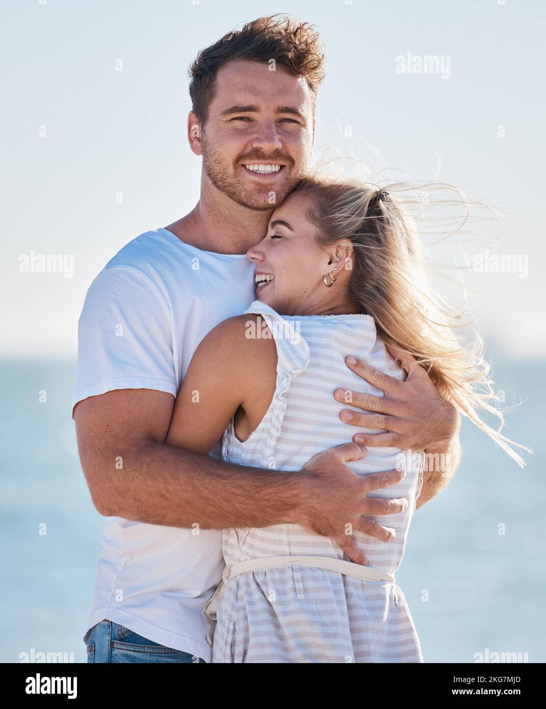 Amore, abbraccio spiaggia e sorriso di coppia sul romantico viaggio di vacanza oceano insieme per legame di rapporto, romanticismo e pace. Faccia di uomo felice, donna con un Foto Stock