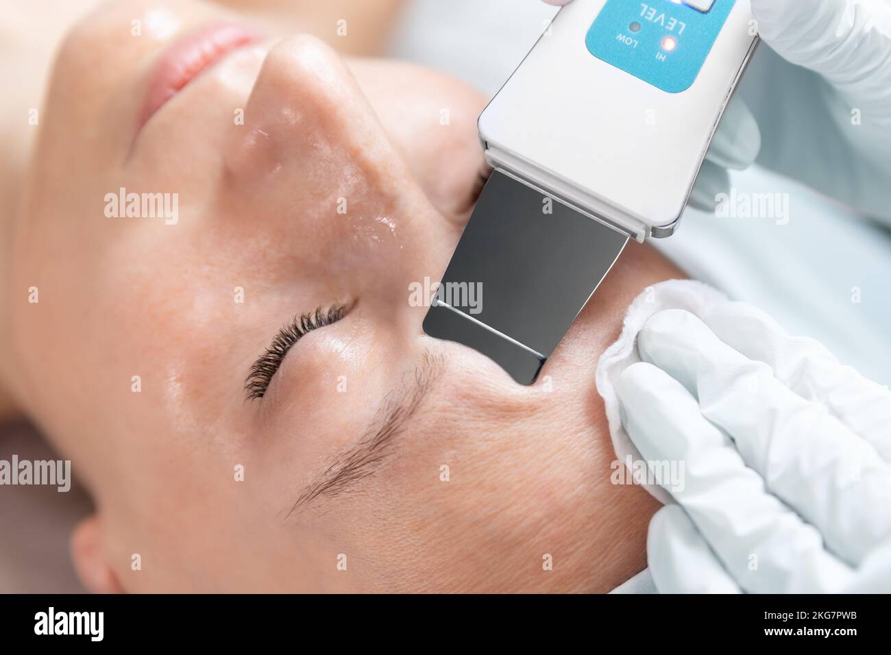 Primo piano dettaglio beautician medico fare cura della pelle peeling procedura di pulizia con ultrasuoni scrubber meccanico spatola al salone di bellezza clinica Foto Stock