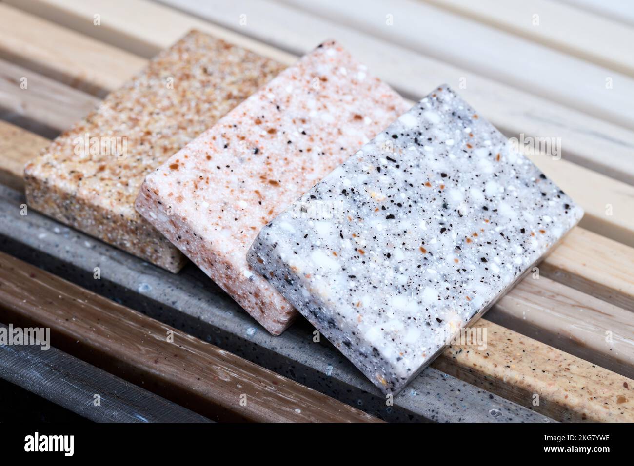 Porcellana tre campioni di pietre quadrate artificiali in gres posati sul piano di lavoro della cucina esempi di futuri esterni della facciata della cucina. Campiona gli strati di Foto Stock