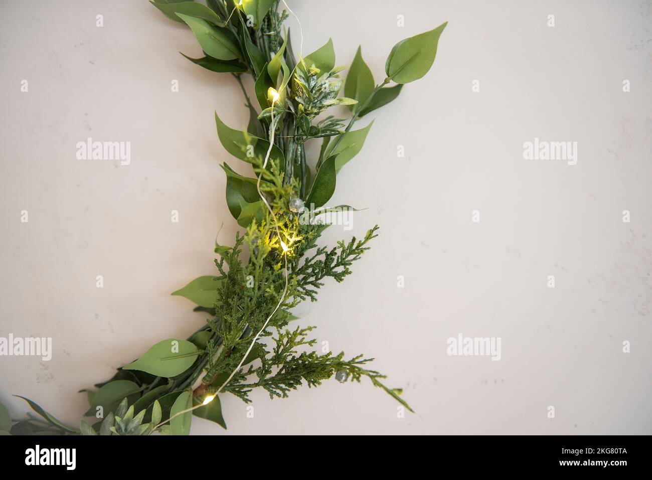 Sulla parete grigia in cemento, sono presenti tre corone lacustiche, eleganti e verdi realizzate con materiali naturali. Garland festivo. Decorazioni minimaliste in ruggine Foto Stock