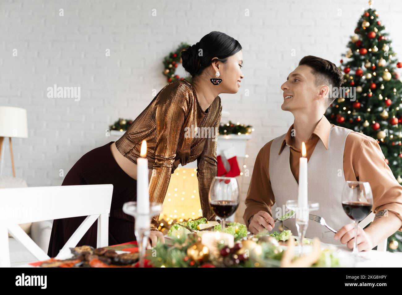 Coppia interrazziale felice che guarda l'un l'altro vicino pasto festivo il giorno di Natale Foto Stock
