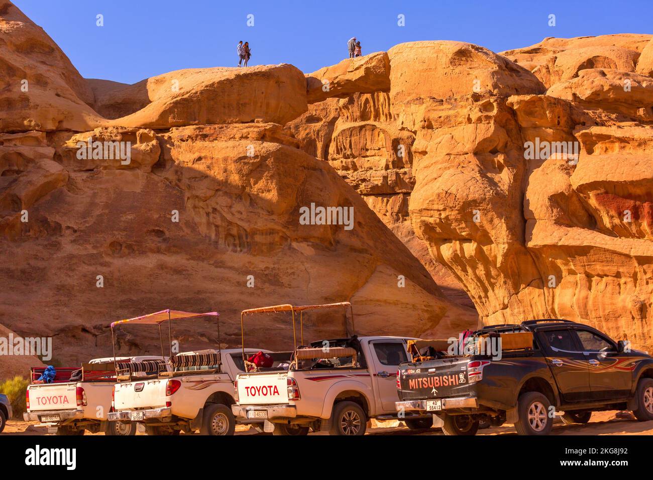 Giordania, Wadi Rum - 2 novembre 2022: Jeep beduina tour auto in piedi vicino a um Frouth ponte di pietra, deserto con scogliera montagna rocciosa sullo sfondo Foto Stock