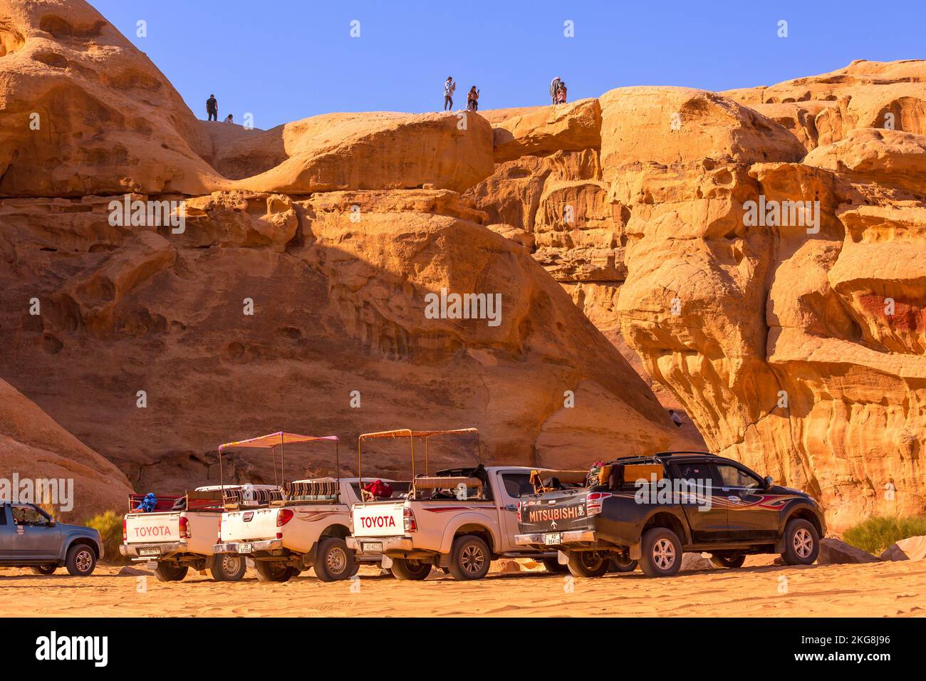 Giordania, Wadi Rum - 2 novembre 2022: Jeep beduina tour auto in piedi vicino a um Frouth ponte di pietra, deserto con scogliera montagna rocciosa sullo sfondo Foto Stock