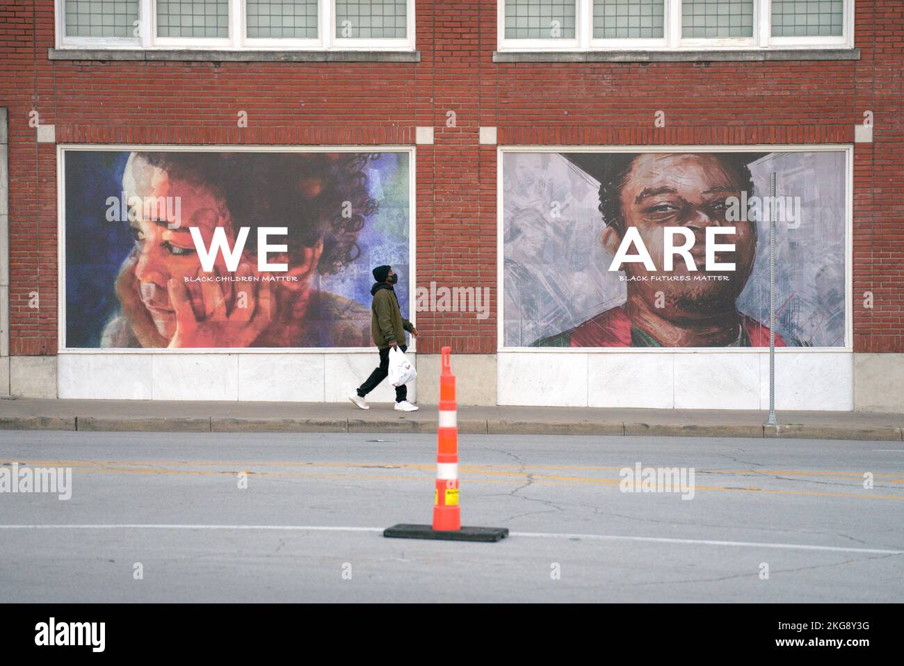 L'uomo passa per le foto di persone sul muro di mattoni rossi. Le vite nere contano. Foto Stock