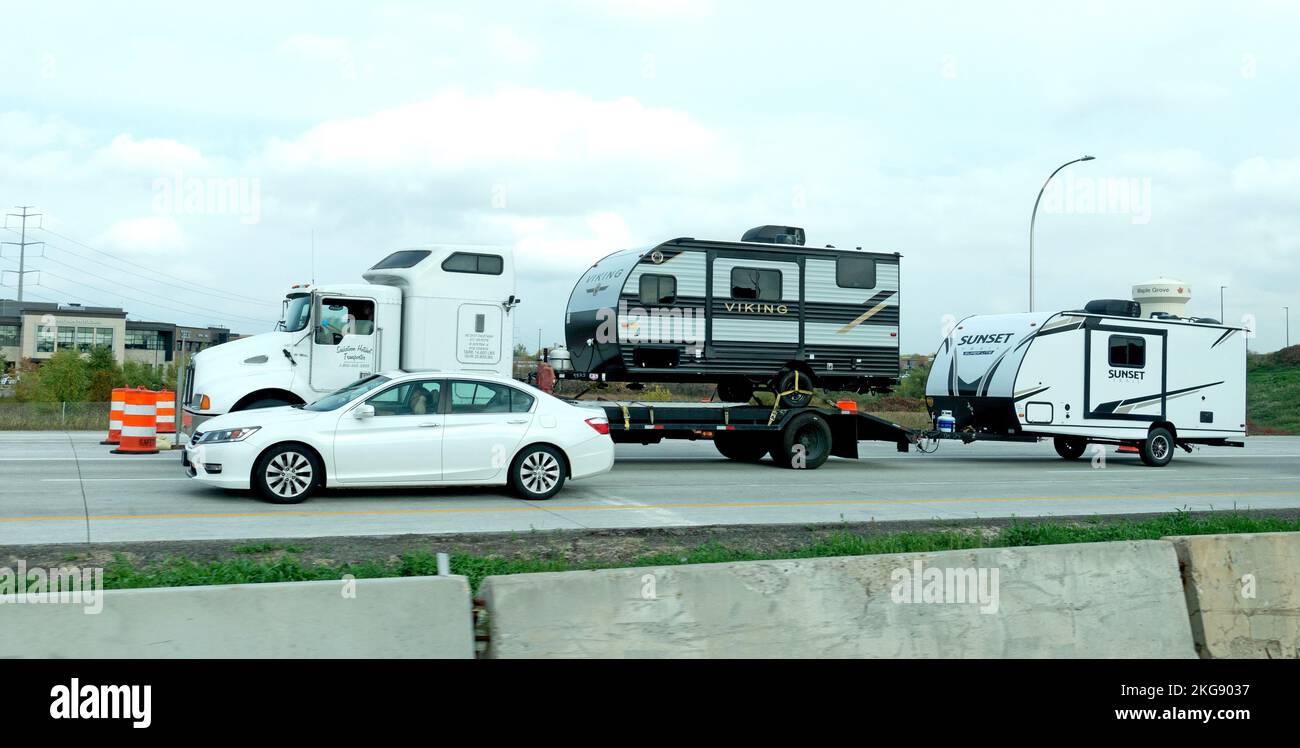 Autocarro che trasporta un rimorchio a casa sul pianale e ne tira un altro mentre si viaggia su strada. Brainerd Minnesota MN USA Foto Stock