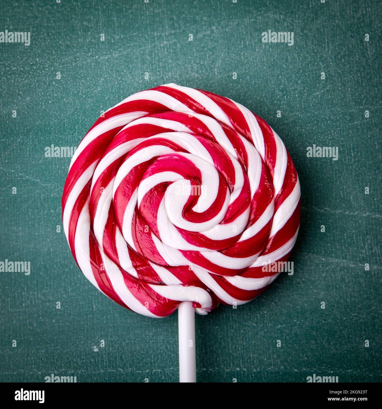 Caramelle rosse e bianche a righe su un bastone, sfondo verde lavagna.  Lollipop Foto stock - Alamy